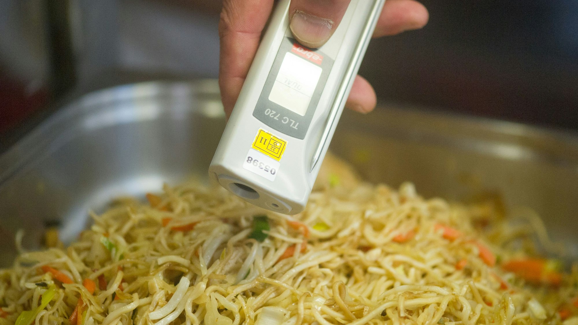 Ein Lebensmittelkontrolleur überprüft bei einer Betriebskontrolle die Temperatur von chinesischen Nudeln.