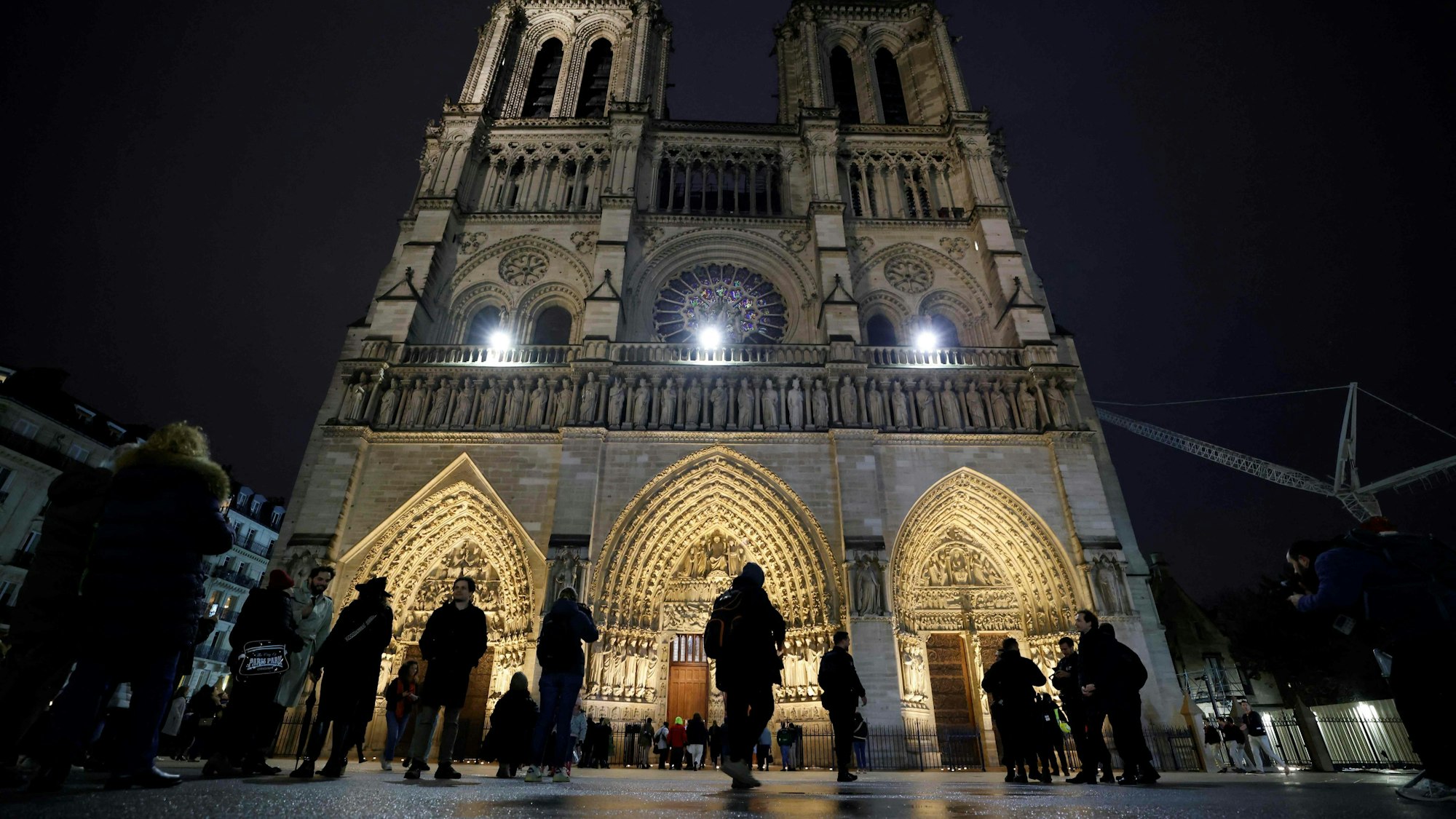 Die Kirche erstrahlt im Dunkeln, Menschen laufen davor.