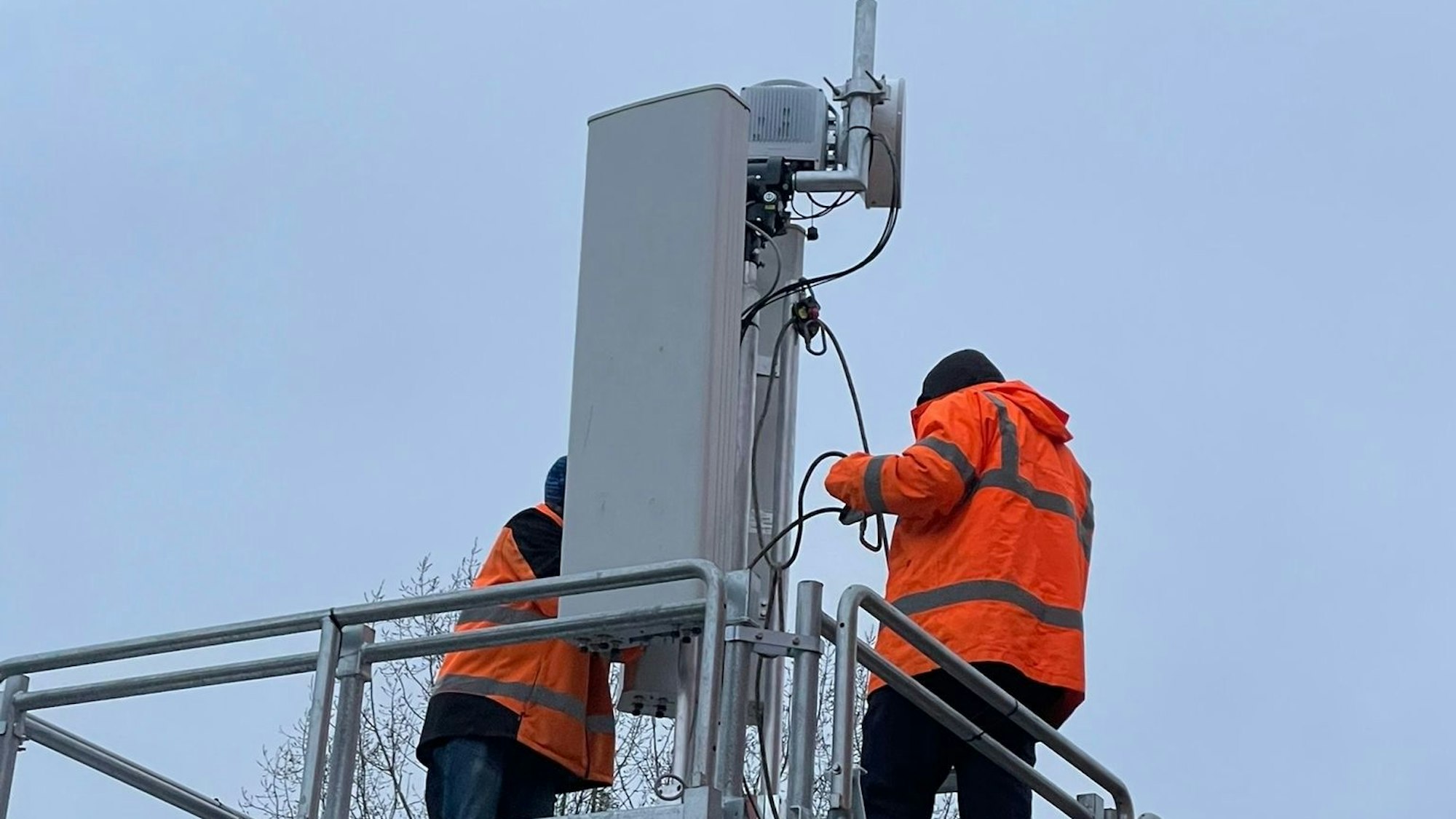Zwei Techniker arbeiten an einem Sendemast.