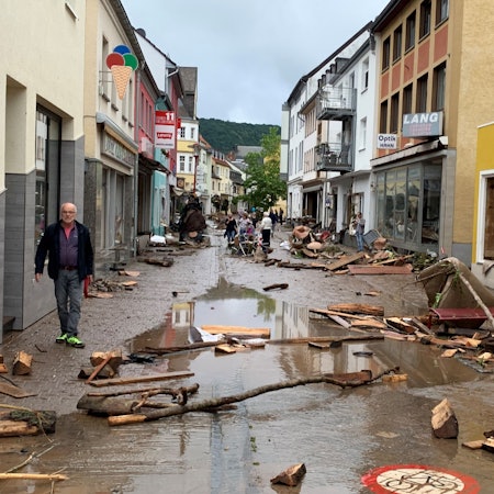 Die Fußgängerzone in Gemünd am Tag nach der Flut 2021. Trümmer, Holz und Müll liegen auf der Straße, die voller Matsch und Pfützen ist.
