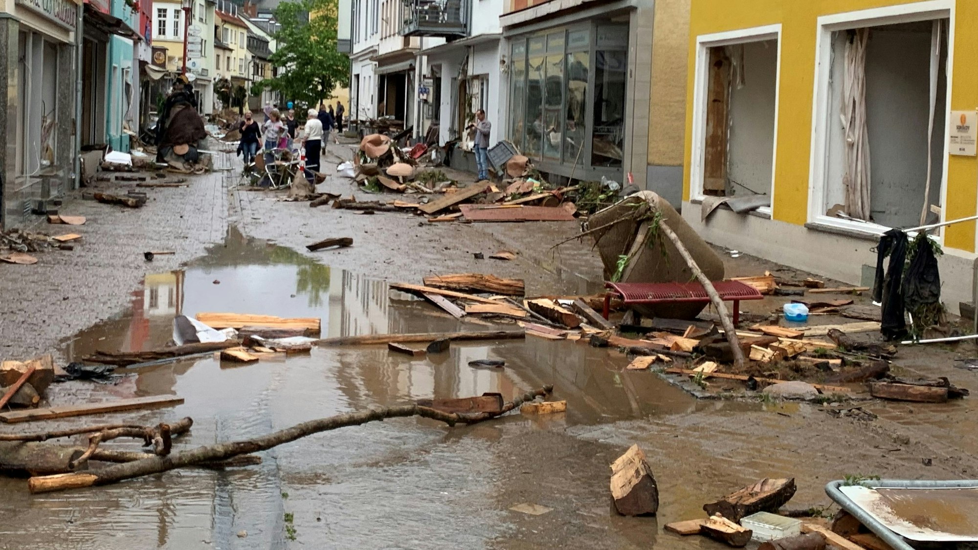 Die Fußgängerzone in Gemünd am Tag nach der Flut 2021. Trümmer, Holz und Müll liegen auf der Straße, die voller Matsch und Pfützen ist.