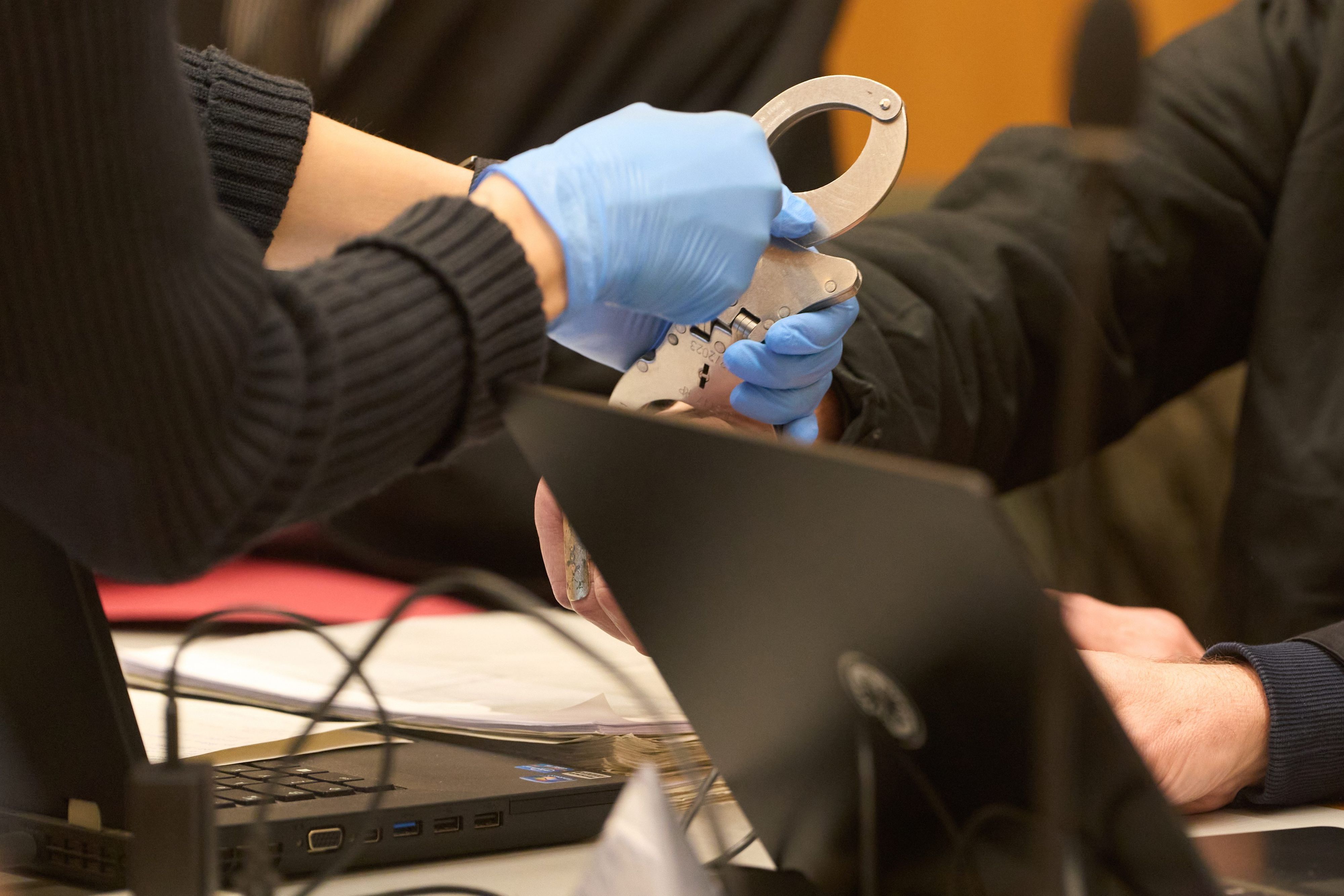 Eine Justizvollzugsbeamtin nimmt einem mutmaßlichen Mitglied der Terrorgruppe „Vereinte Patrioten“ im Gerichtssaal die Handschellen ab.