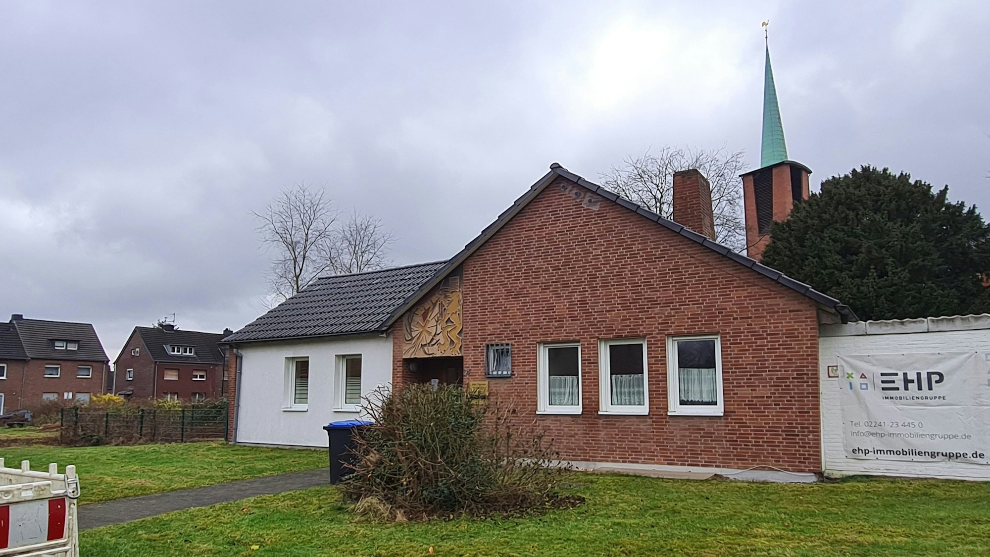 Das Foto zeigt ein altes Pfarrhaus vor der Kirche.