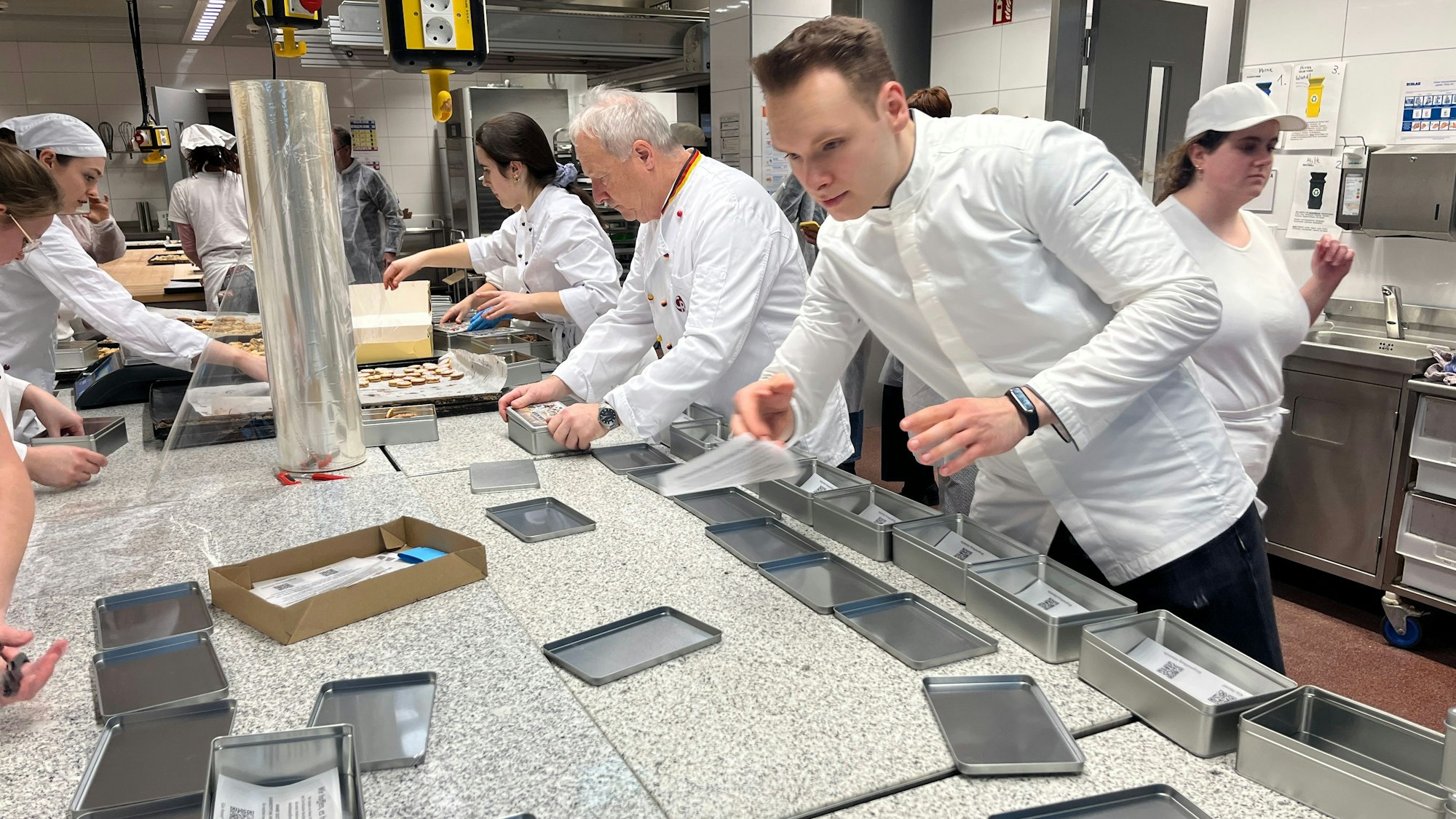 Ein Konditor bereitet Metalldosen vor, um Gebäck zu verpacken.