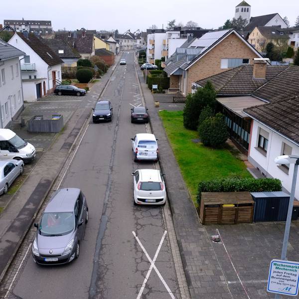 Die Feytalstraße in Mechernich führt von der Ortsmitte zum Schulzentrum. Am rechten Straßenrand parken drei Autos auf der Fahrbahn.