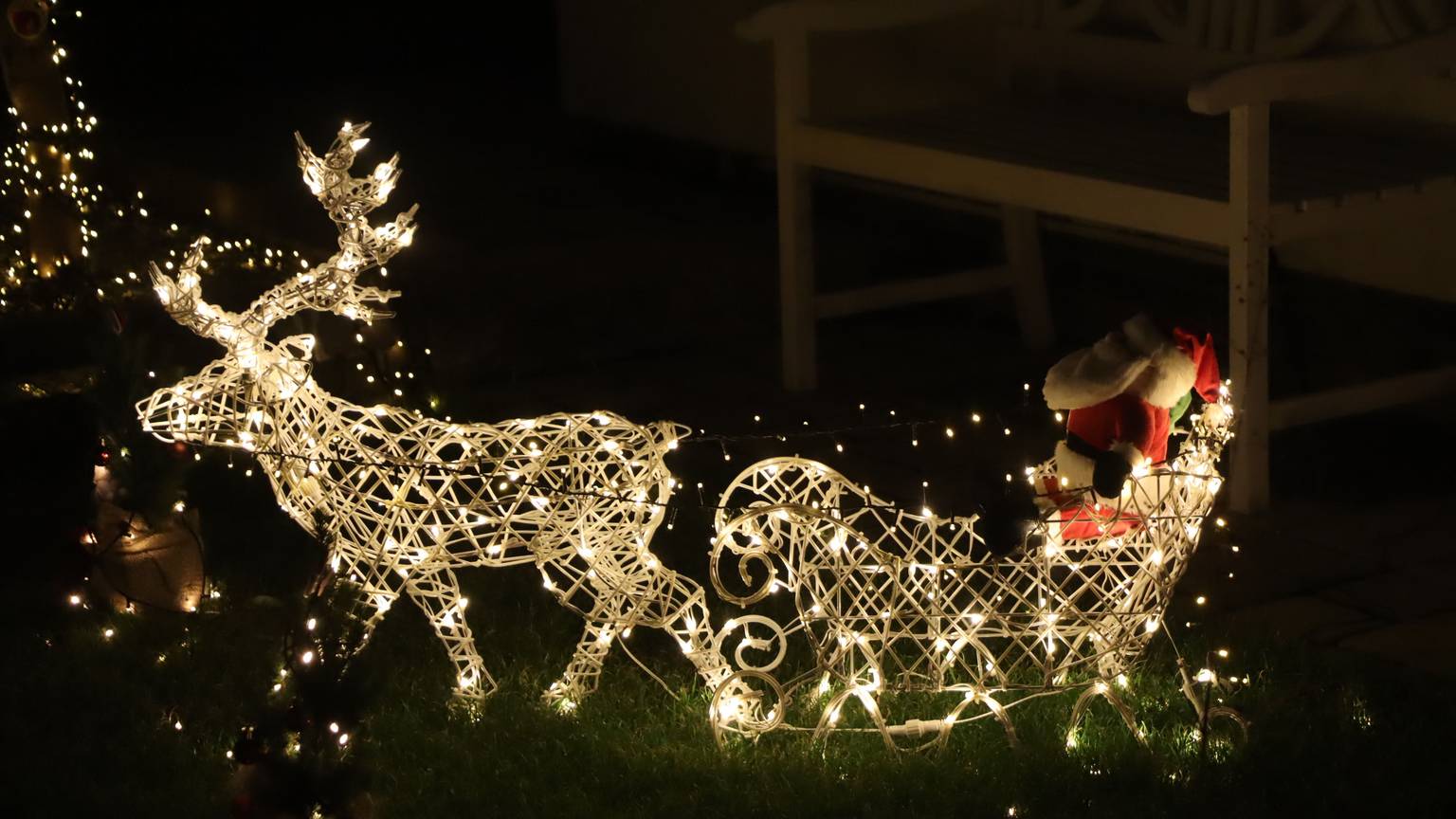 Ein beleuchteter Schlitten mit Weihnachtsman, gezogen von einem Rentier.