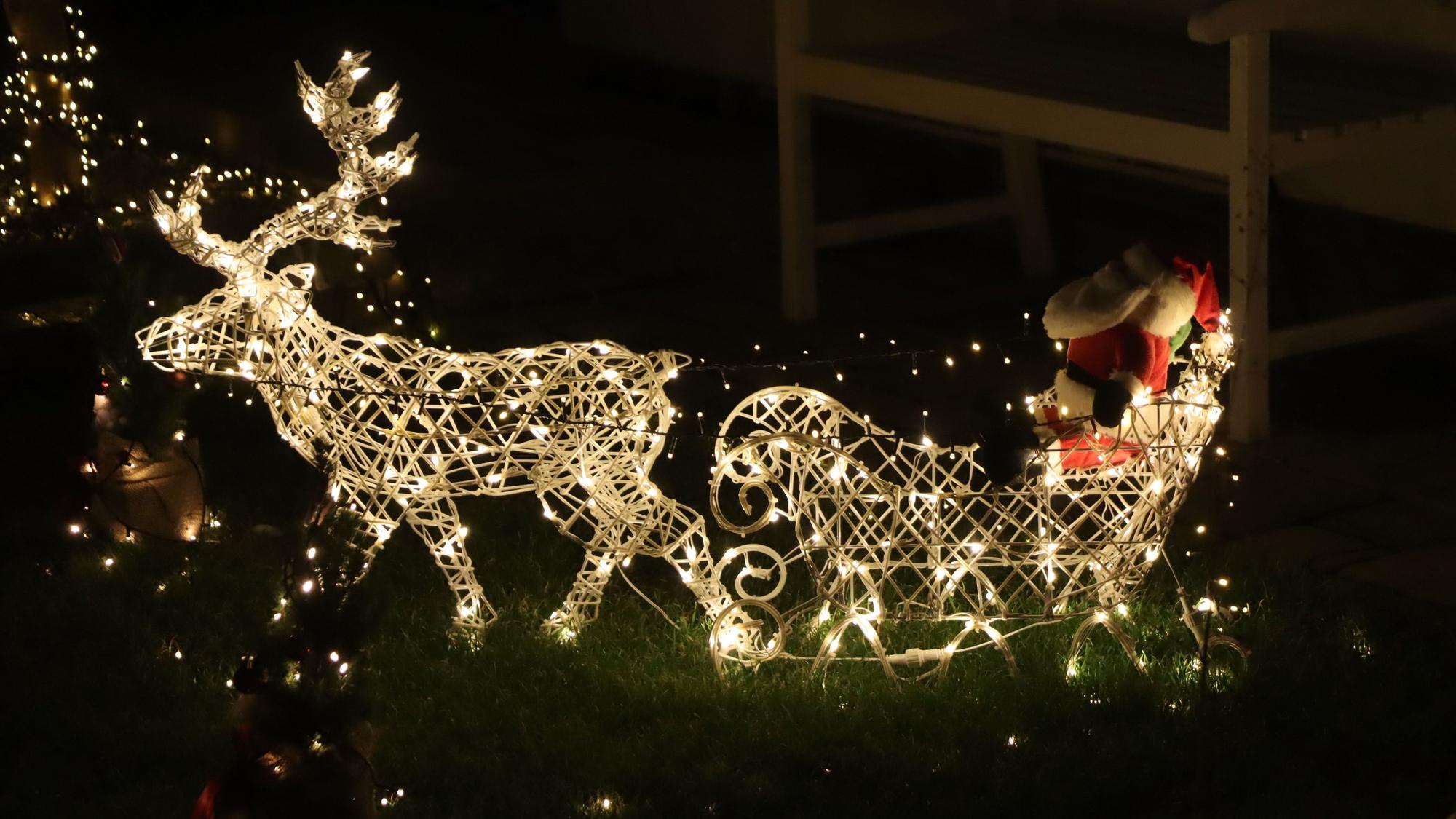 Ein beleuchteter Schlitten mit Weihnachtsman, gezogen von einem Rentier.