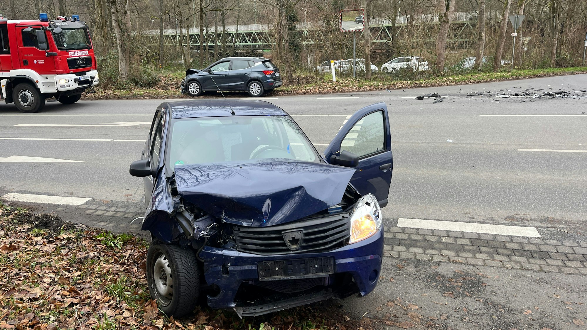 Zwei Autos stehen nach einem Zusammenstoß auf den gegenüberliegenden Straßenseiten neben einem Feuerwehrauto..