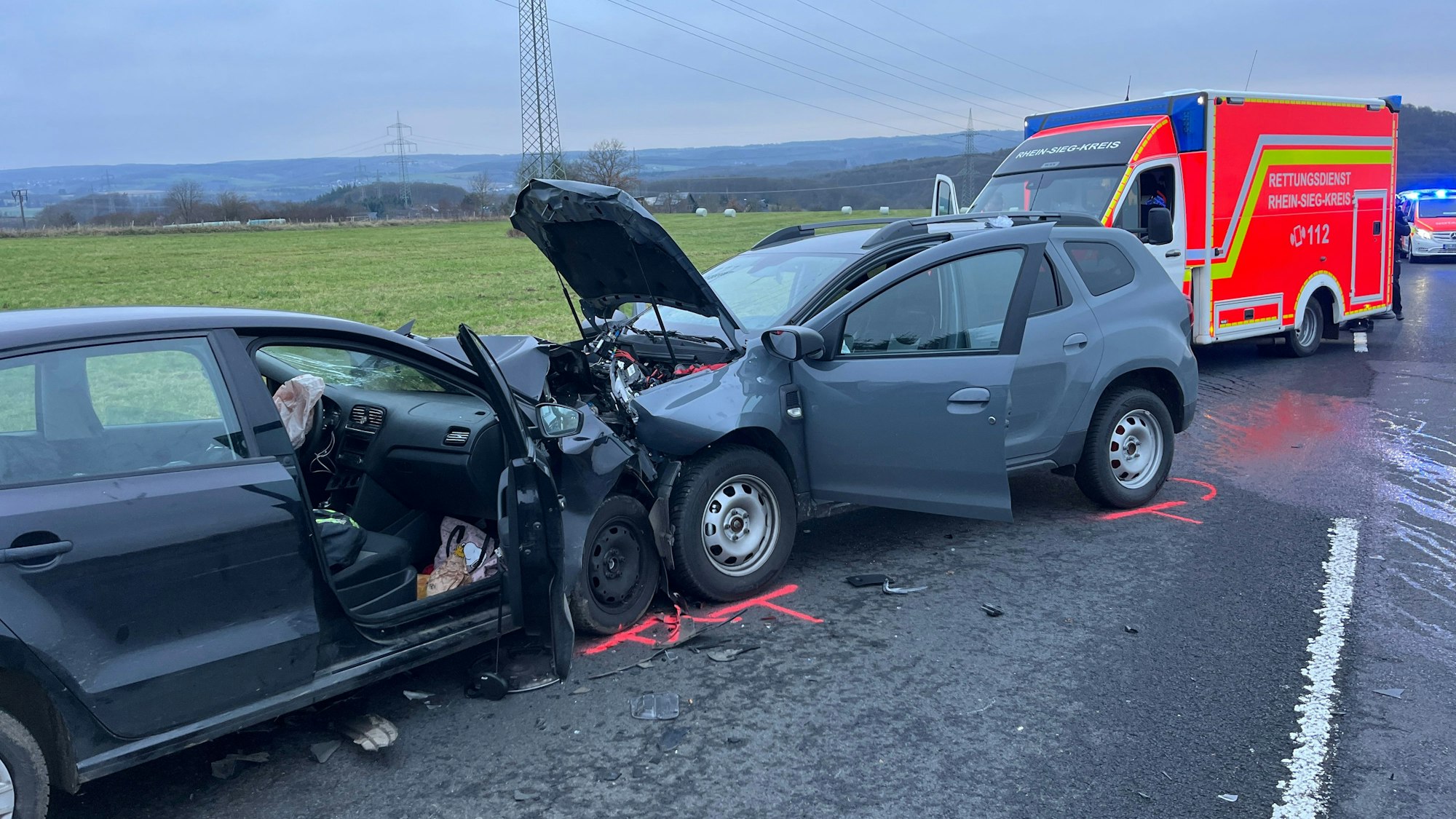 Nach einem Zusammenstoß stehen zwei Autos auf der Straße, dahinter Rettungswagen und Notarzt.