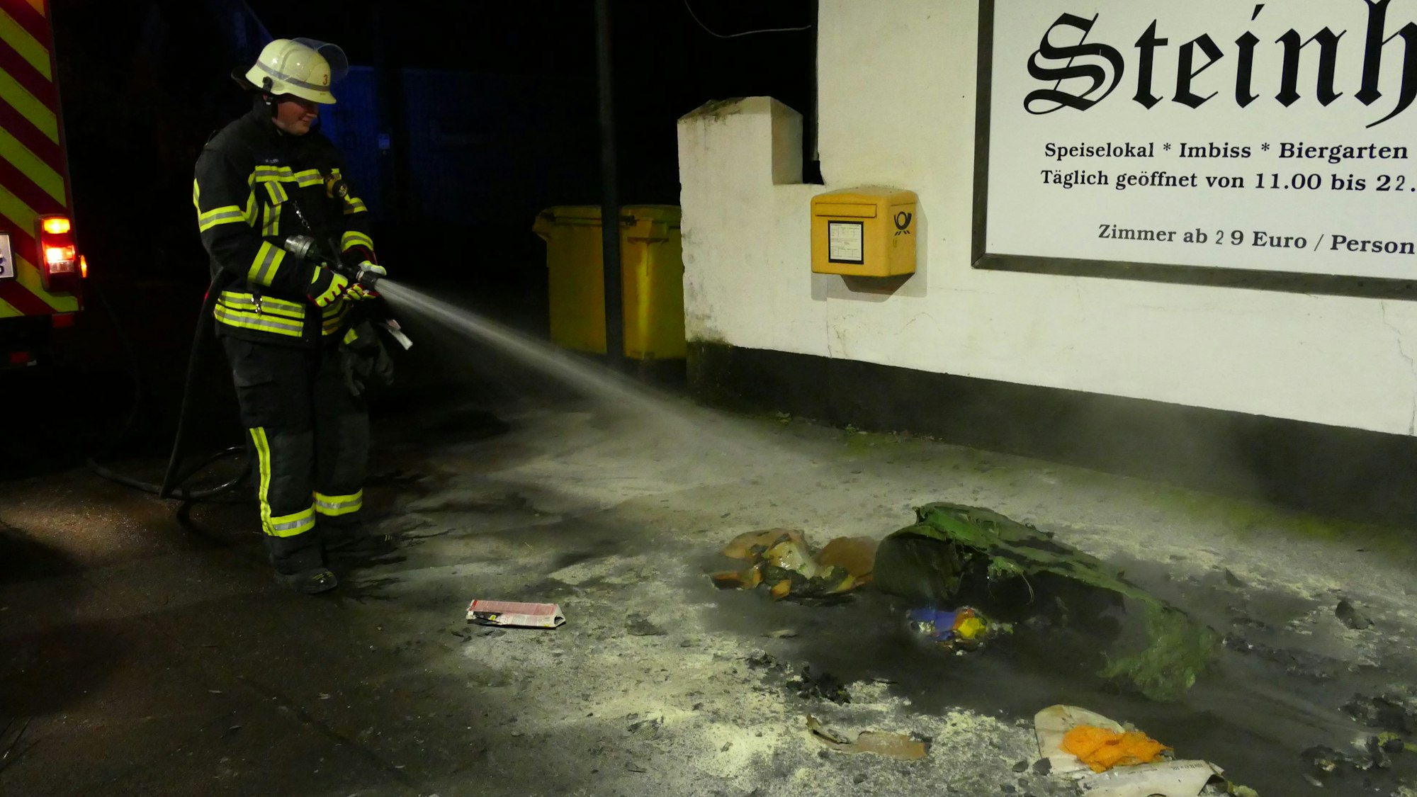 Ein Feuerwehrmann löscht eine brennende Papiertonne.