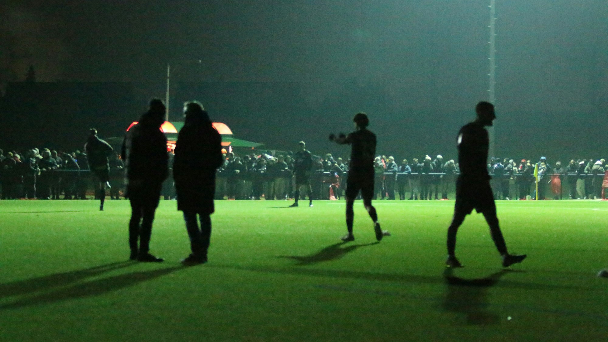 Die Spieler machen sich im Schatten warm. Ein Teil der Flutlichtanlage funktioniert bereits wieder.