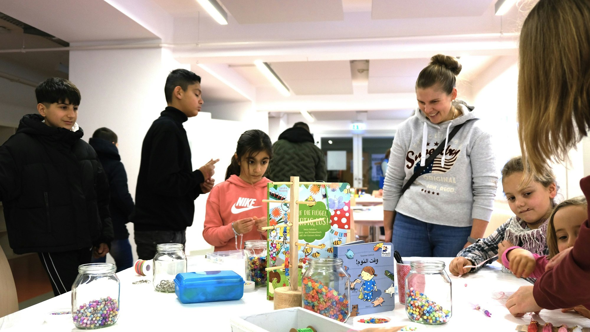 An einem Tisch basteln Kinder. Drumherum stehen zwei Jugendliche und eine Frau.