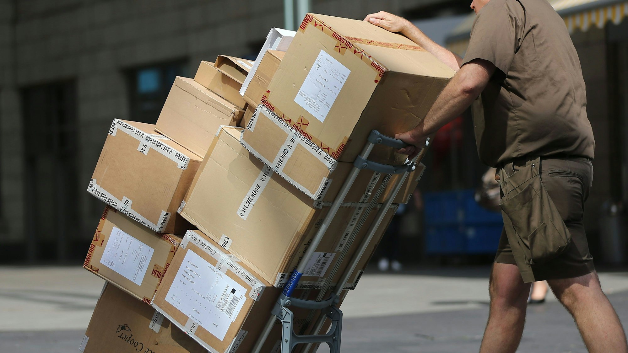 ARCHIV - 14.08.2013, Nordrhein-Westfalen, Köln: ILLUSTRATION - Ein Paketbote liefert Pakete aus.