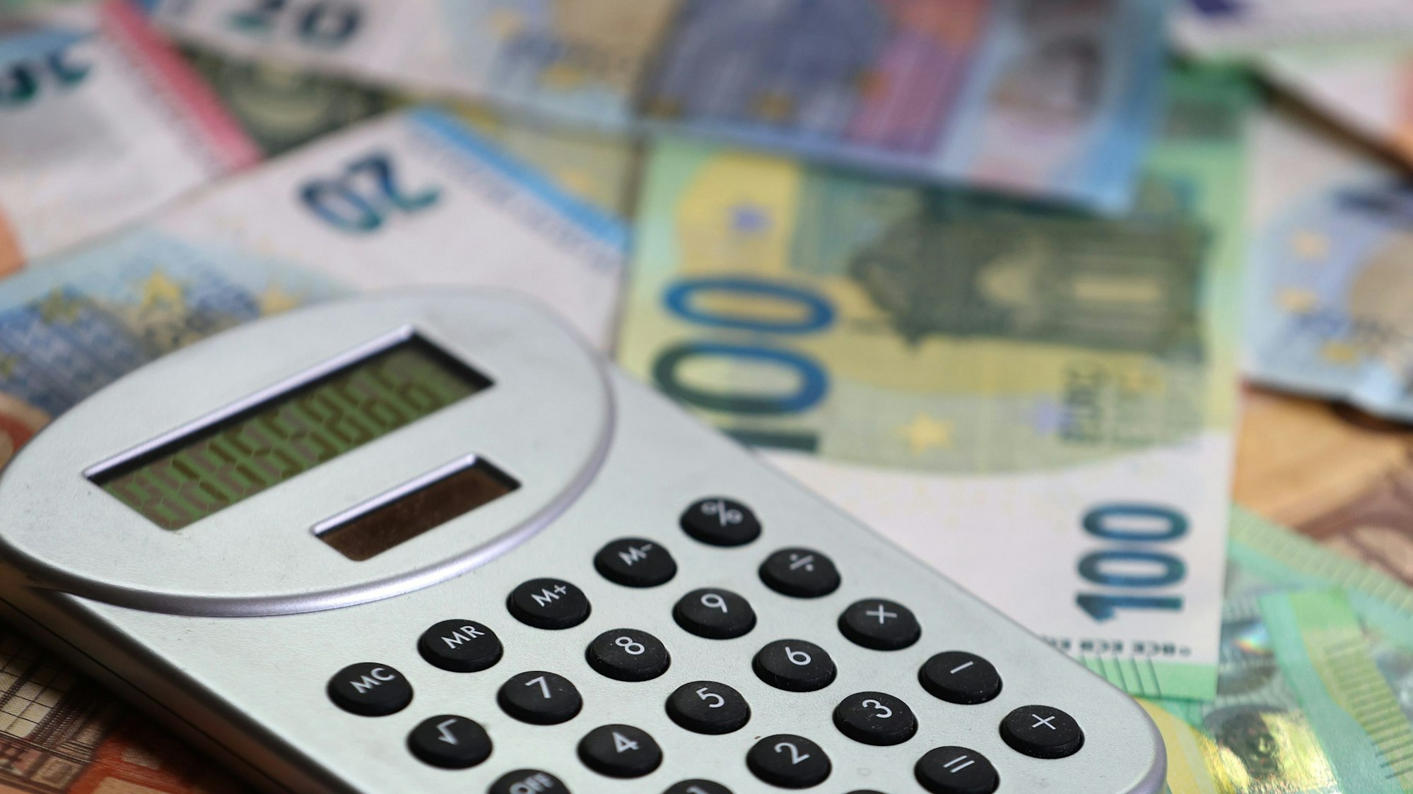 Ein Taschenrechner liegt auf verschiedenen Euro-Banknoten.