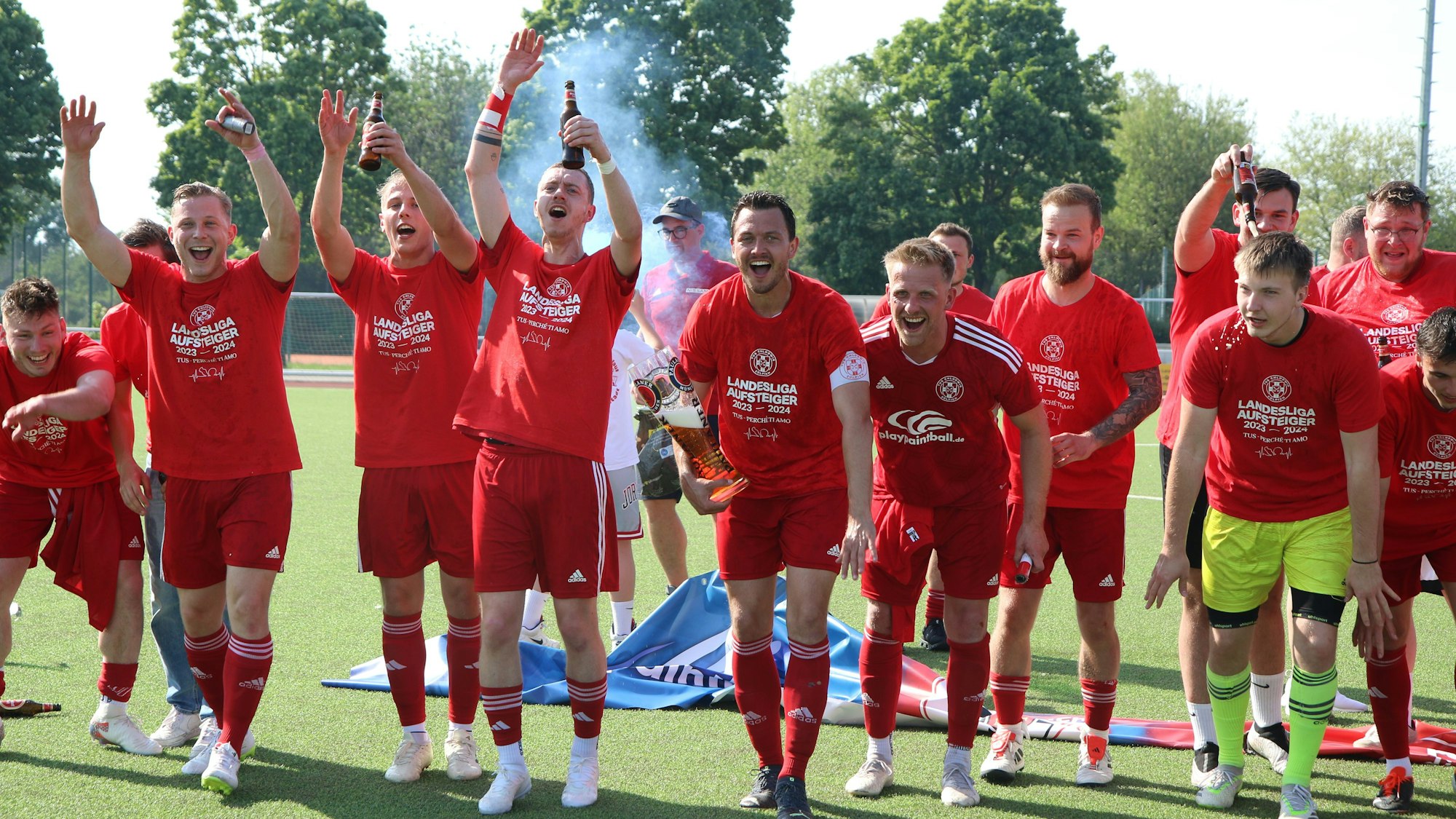 Die Spieler des TuS Zülpich freuen sich über ihren Aufstieg. Sie feiern, halten Bierflaschen und Arme in die Höhe und animieren die Fans.