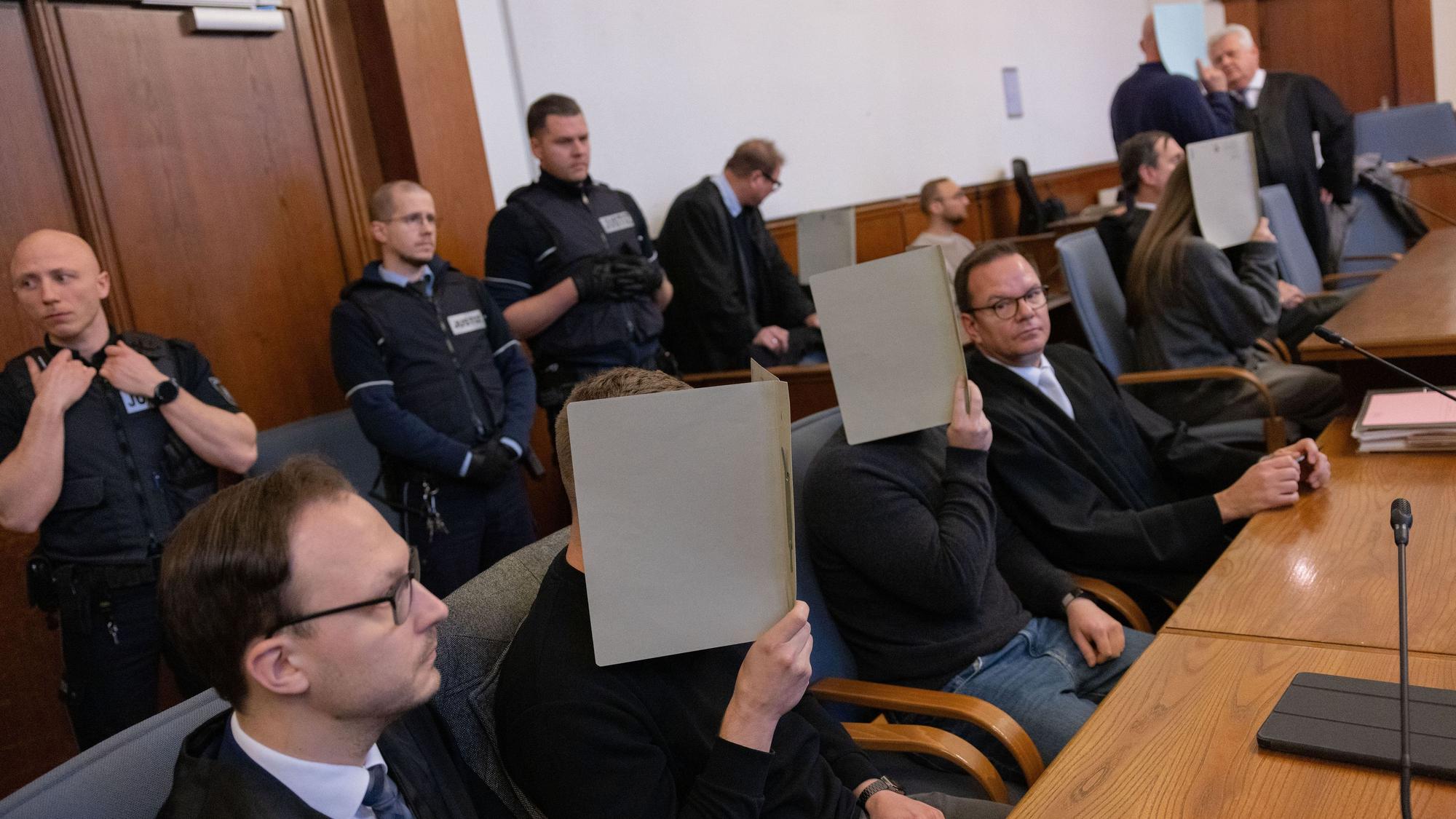 Die fünf Angeklagten Polizeibeamten im Gerichtssaal des Landgerichts. Sie halten sich Ordner vor die Gesichter.