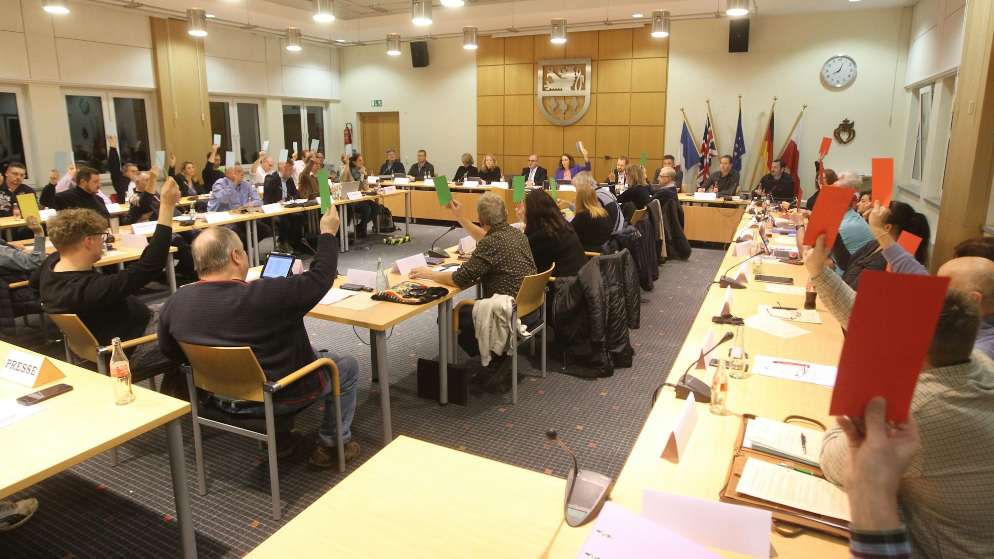 In einem Sitzungssaal heben Menschen rotze und grüne Karten in die Höhe.