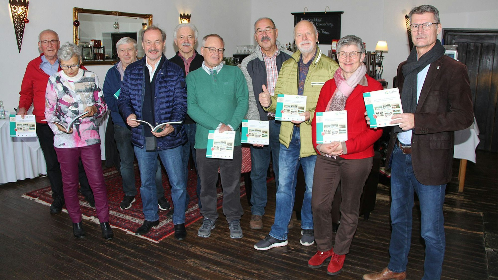 Eine Gruppe von Männern und Frauen posiert für ein Foto, sie halten ein Buch in den Händen.