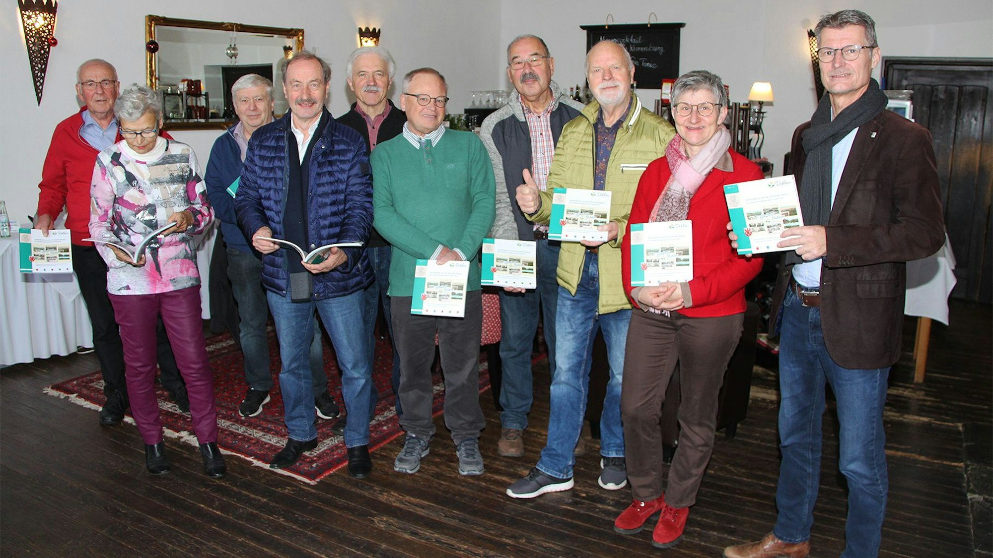 Eine Gruppe von Männern und Frauen posiert für ein Foto, sie halten ein Buch in den Händen.