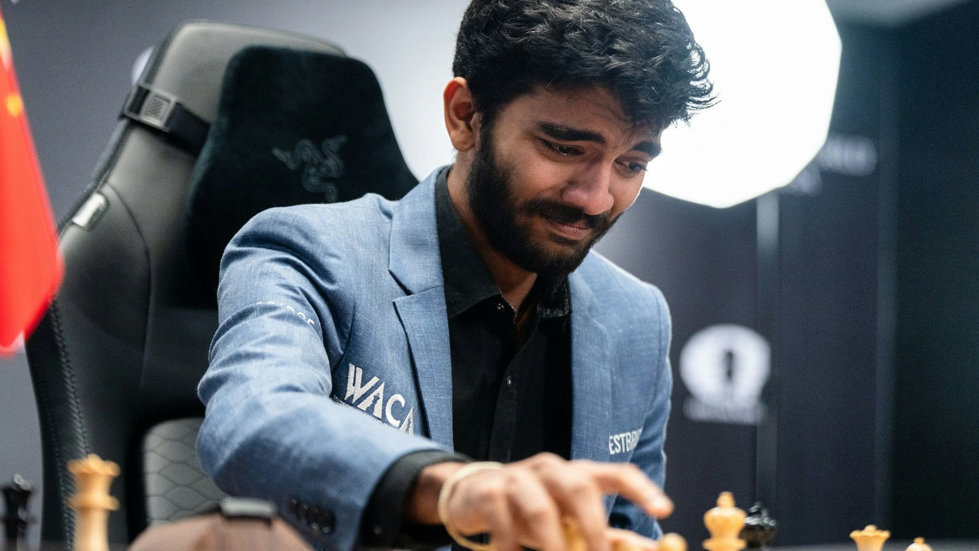 Dommaraju Gukesh hat Tränen in den Augen und setzt eine Schachfigur.