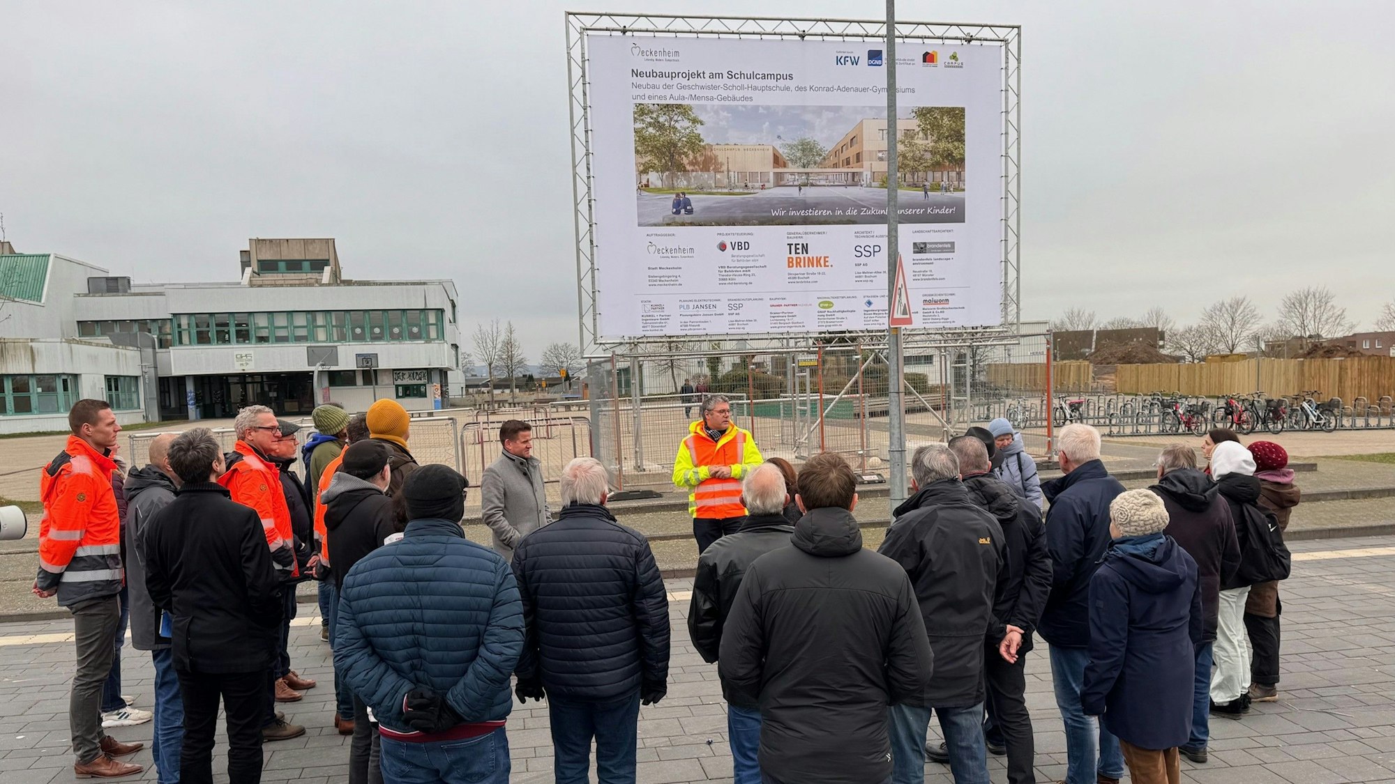 Andreas Satzer (mit Warnweste) steht vor der Gruppe und erklärt den Baufortschritt.