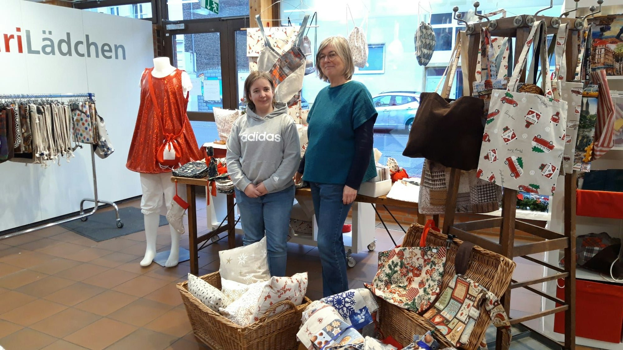Zwei Frauen stehen inmitten von selbstgenähten Kissen, Taschen und Kleidung.