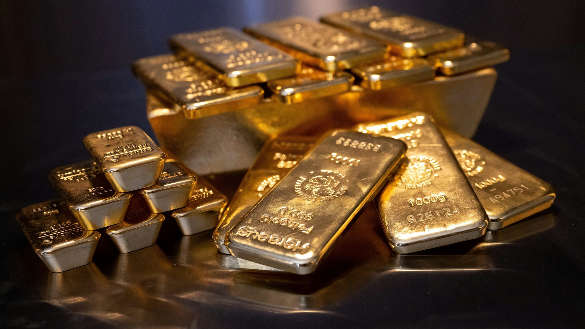 Goldbarren in unterschiedlicher Größe liegen bei einem Edelmetallhändler in einem Tresor auf einem Tisch.