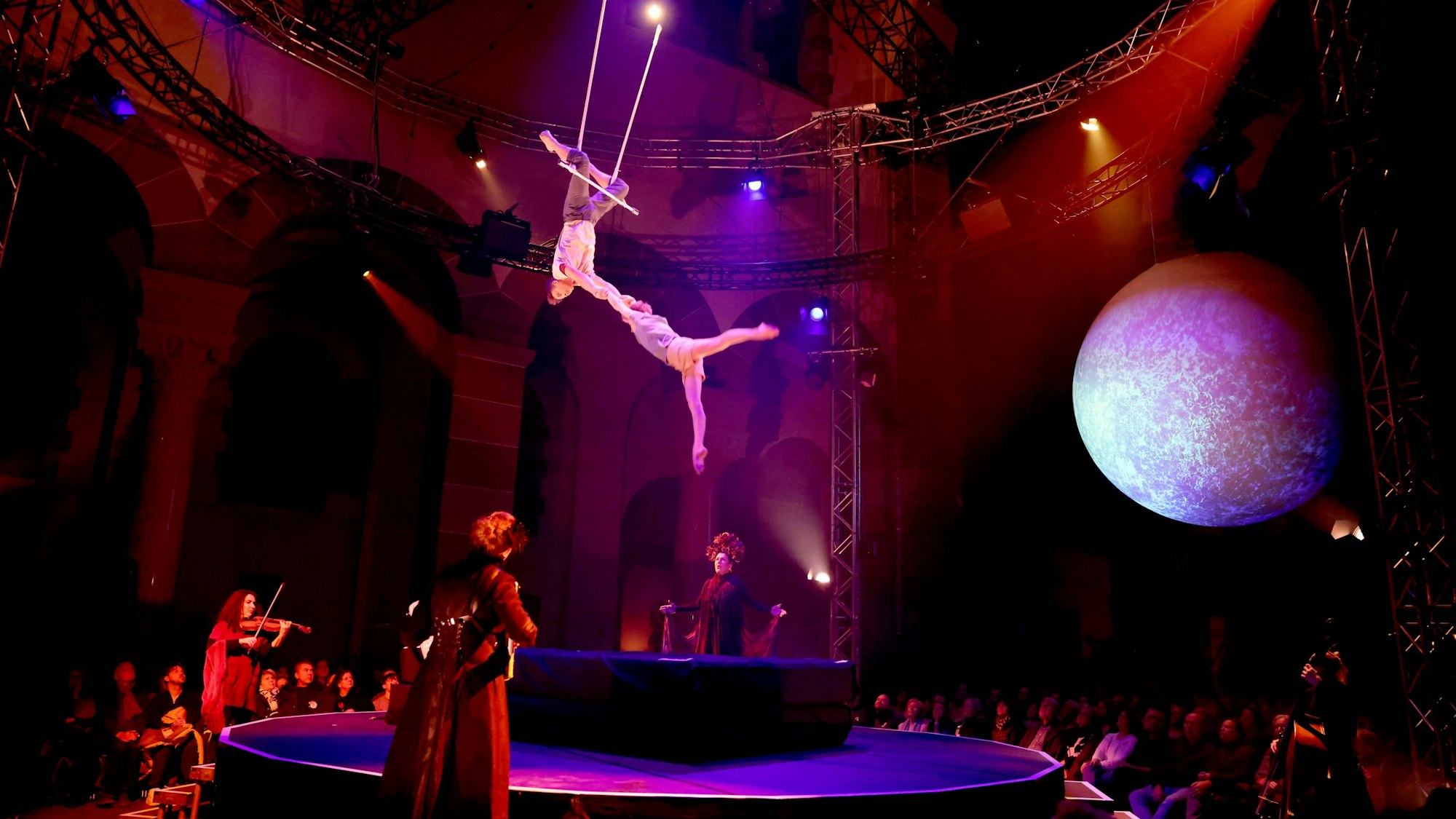 Unter den hohen Kirchendecken fliegt das Akrobatenteam des Zirkus über die Köpfe des Publikums.