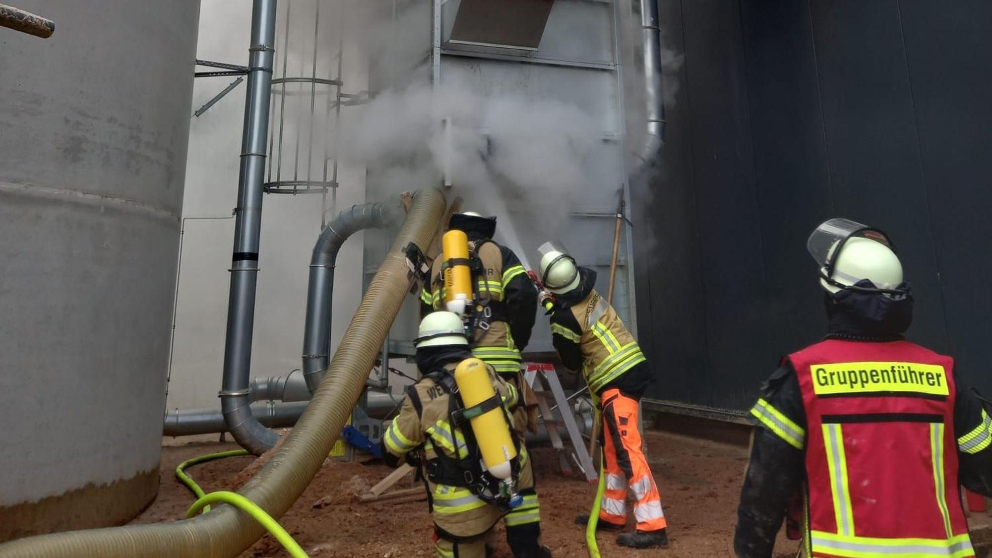 Feuerwehrleute bekämpfen das Feuer in der Filteranlage mit dem Wasser aus einem Schlauch.
