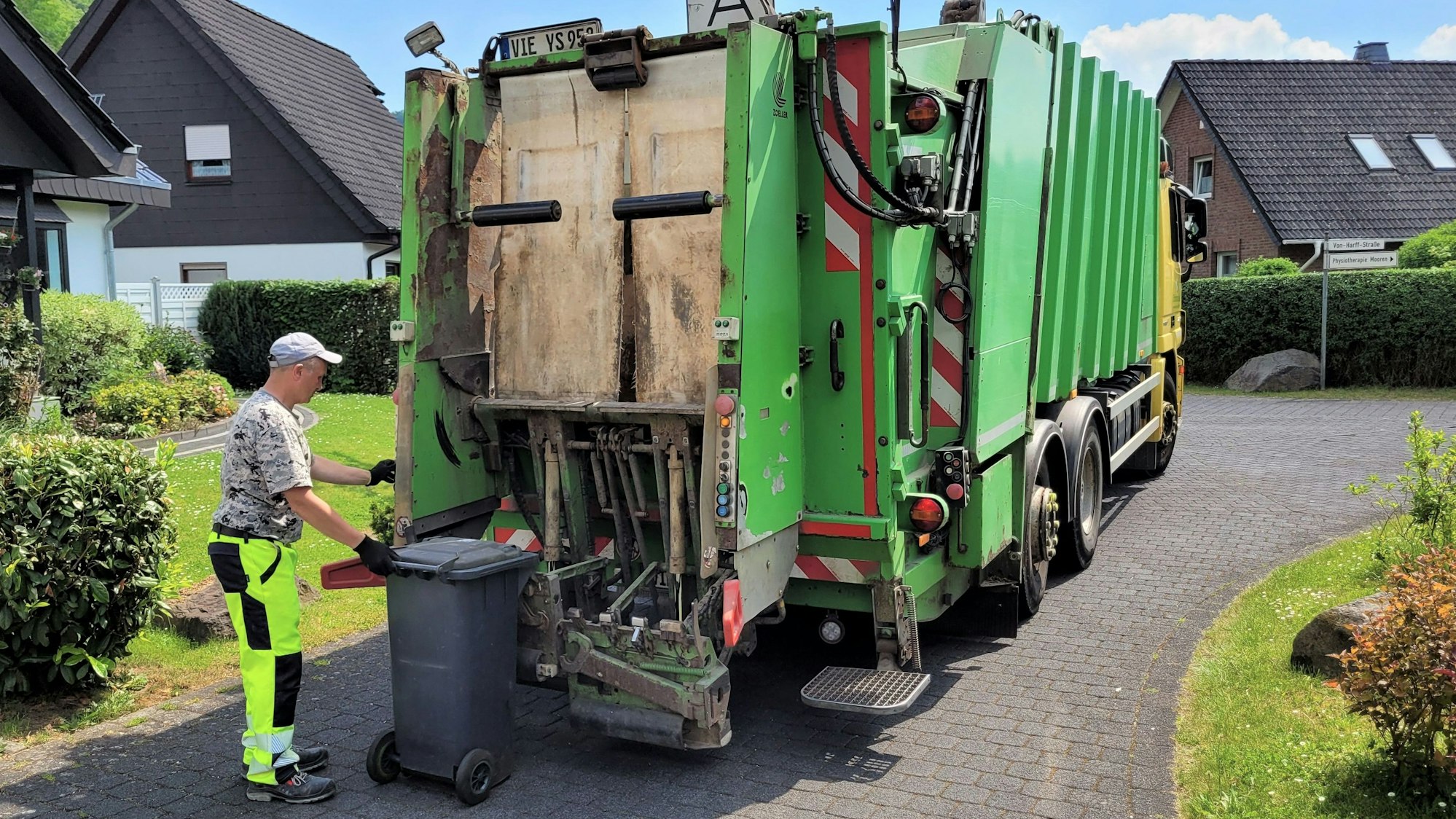 Ein Mitarbeiter der Müllabfuhr entleert eine Mülltonne in das Müllfahrzeug.
