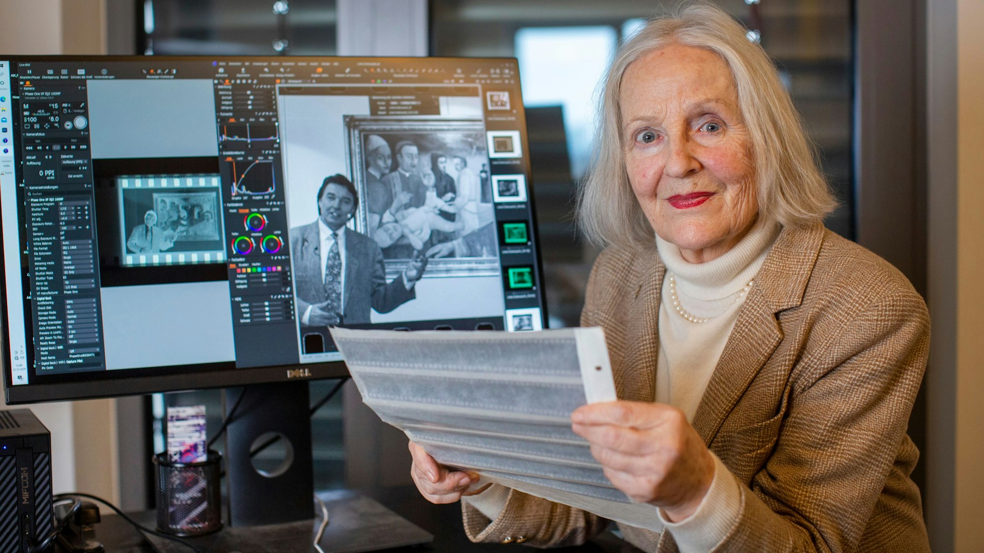 Eine Frau hält Negative in der Hand und blickt in die Kamera.