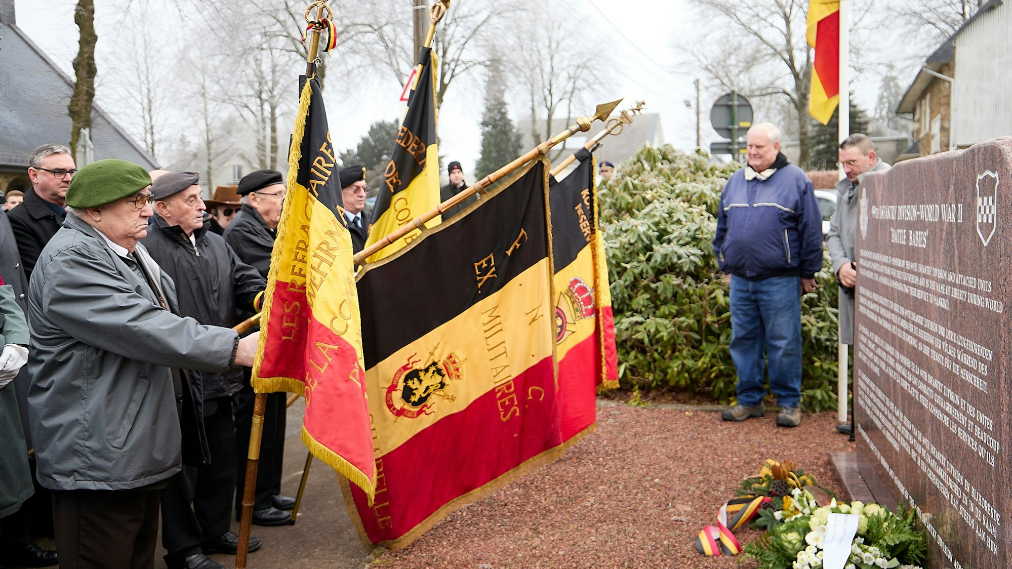 Die belgischen Veteranen senken ihre Fahnen vor dem Denkmal.