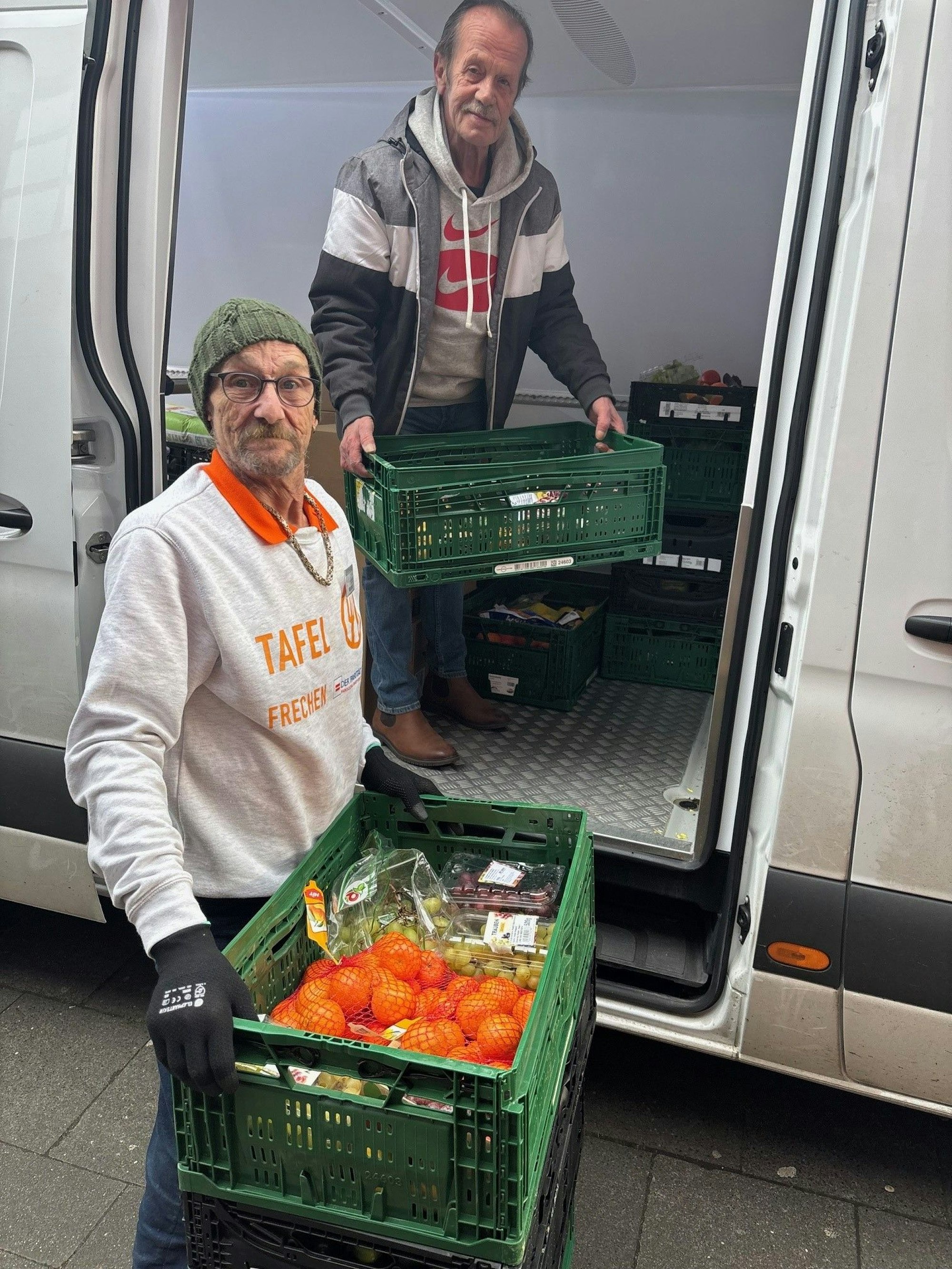 Auf dem Bild sind zwei Männer zu sehen, die Lebensmittel aus einem Transporter heben.