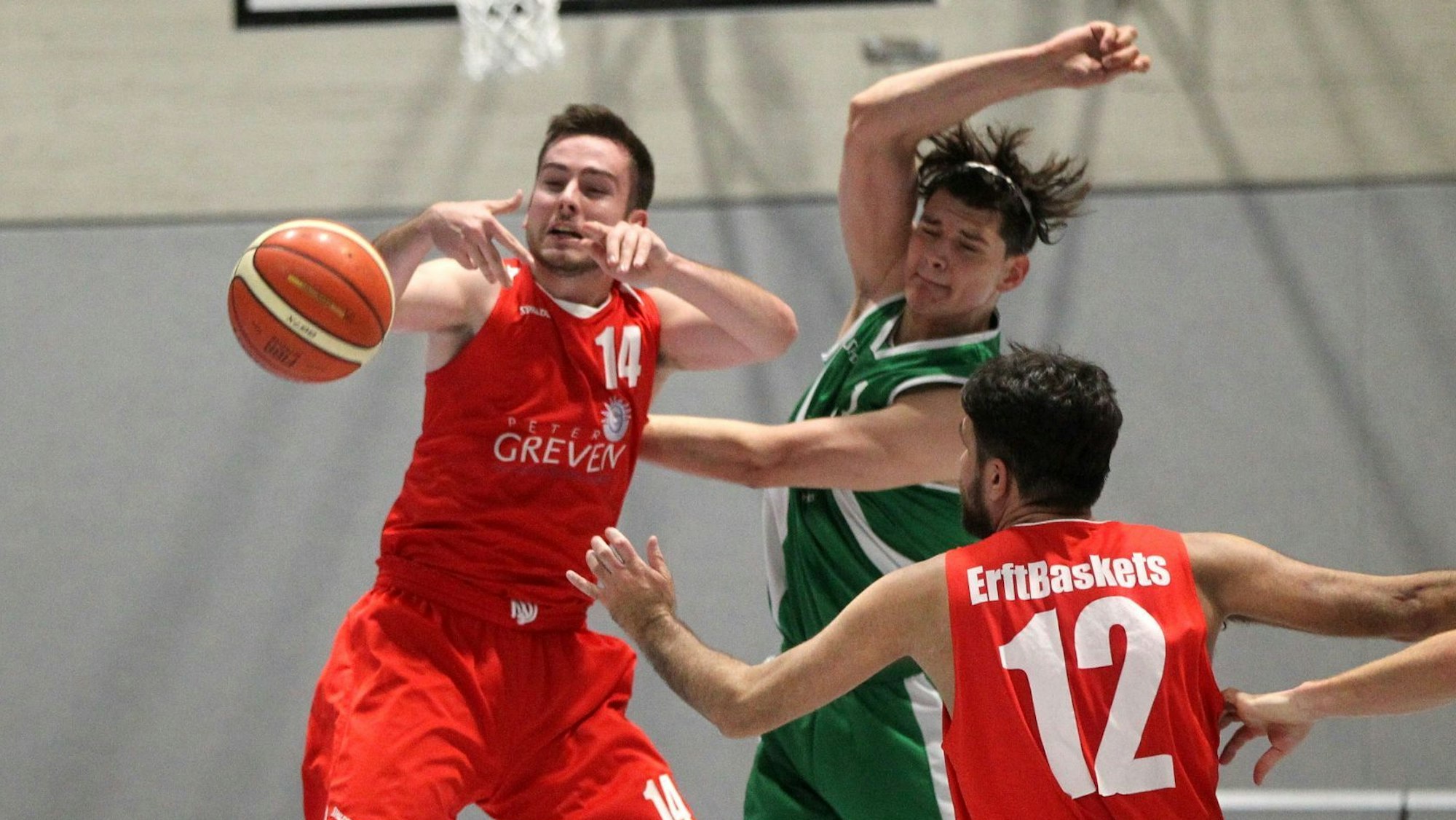Ein Basketballer wirft einen Ball, wird aber von der Seite attackiert.
