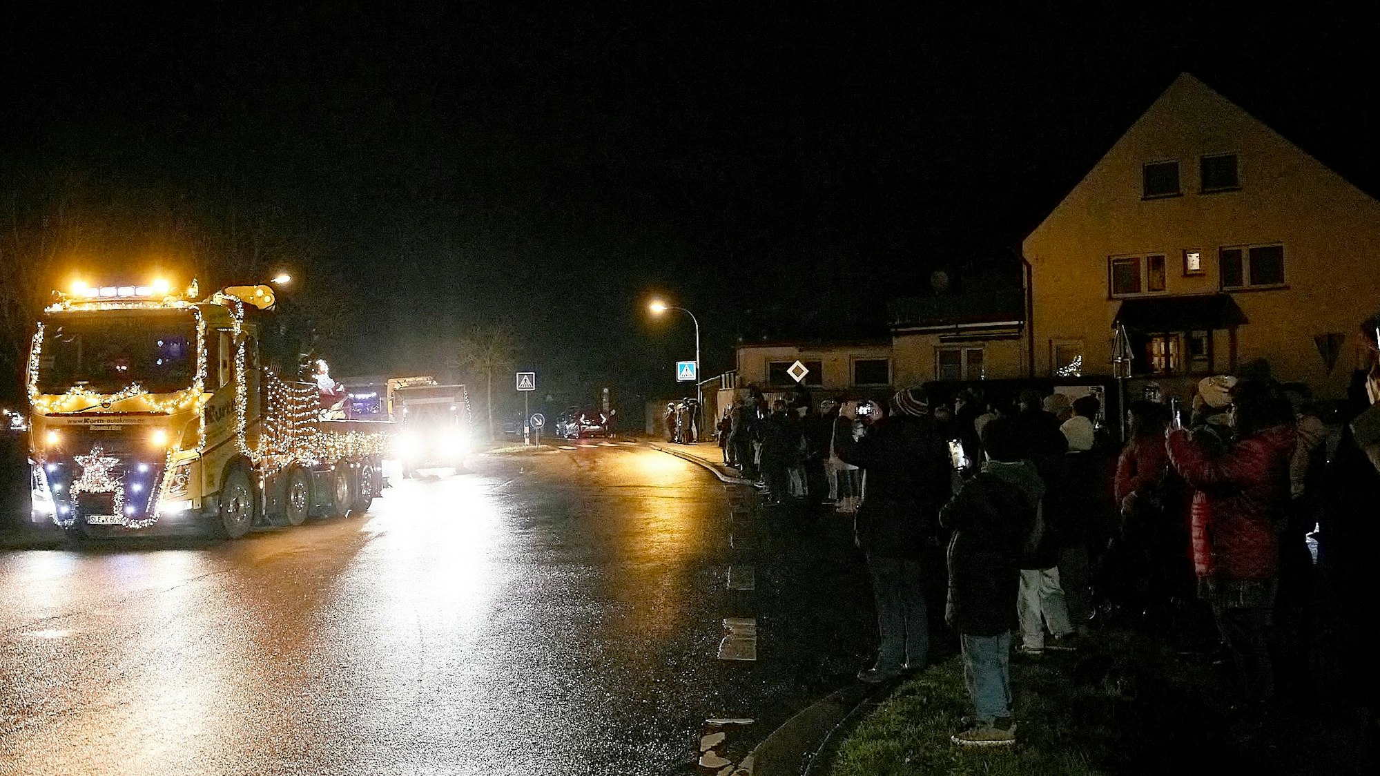 Während die Lkw heranrollen, zucken eine Reihe von Zuschauern ihre Handys, um den Moment festzuhalten.