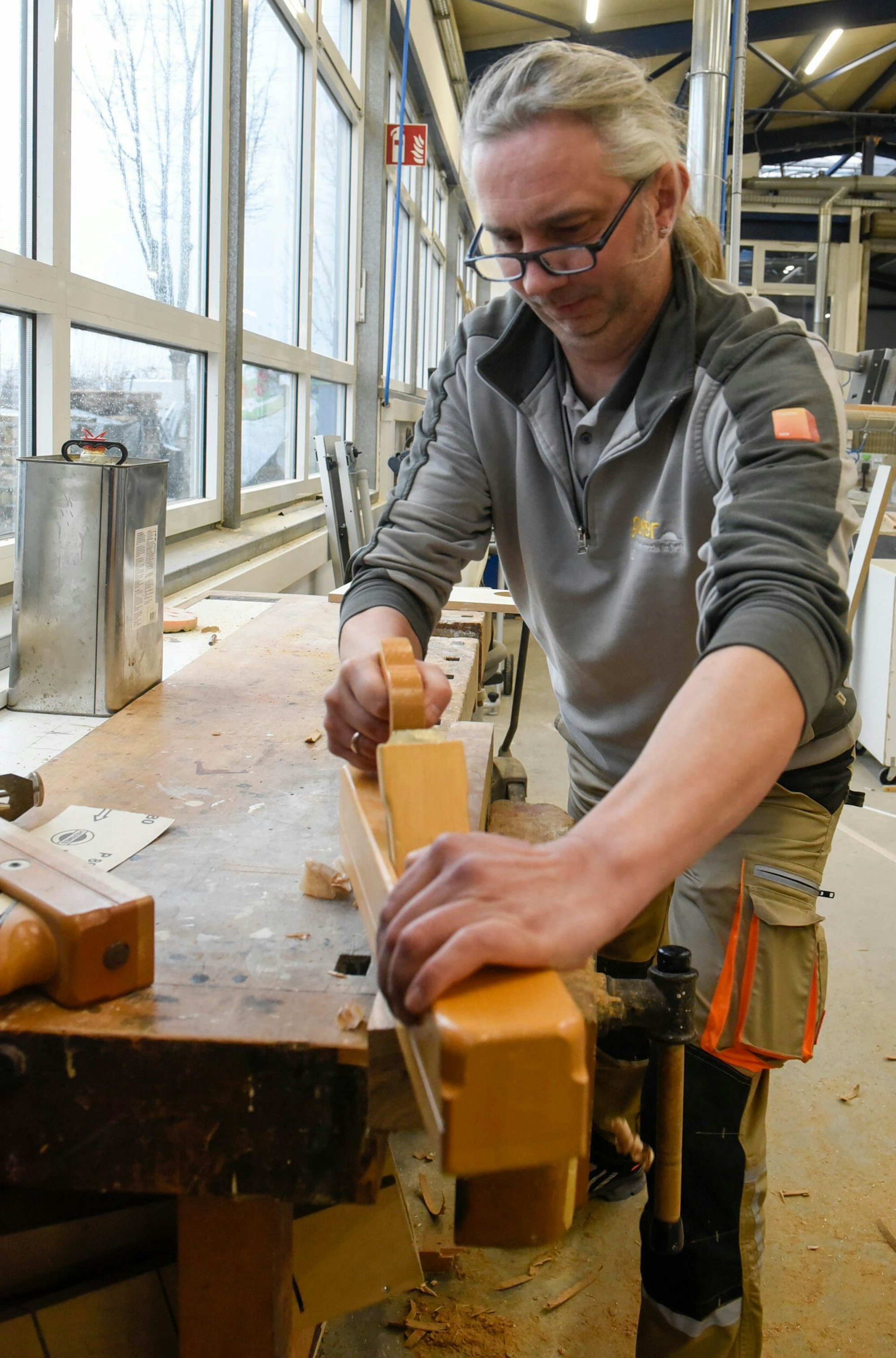 Auf dem Bild ist ein Tischler mit Handhobel zu sehen.