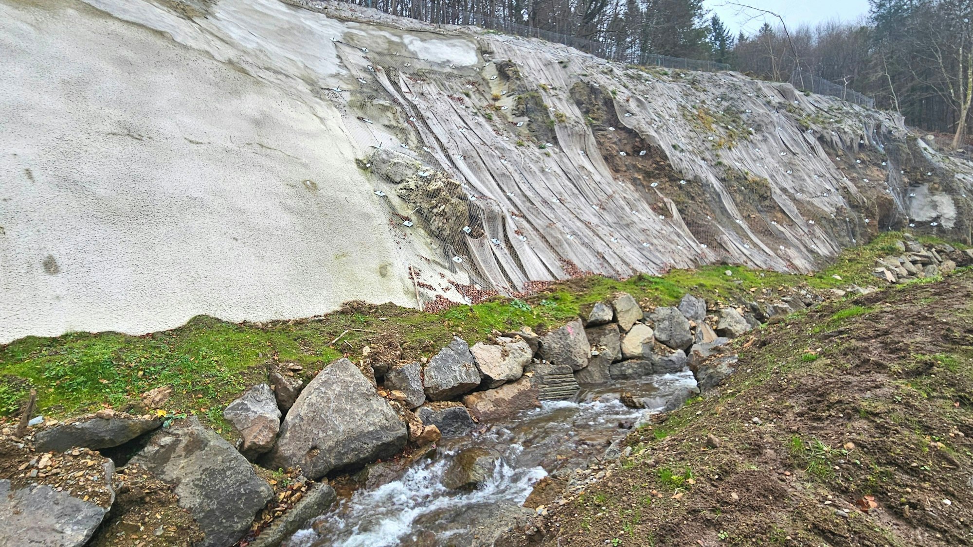 Blick auf den mit Spritzbeton stabilisierten Hang und den Gillesbach.