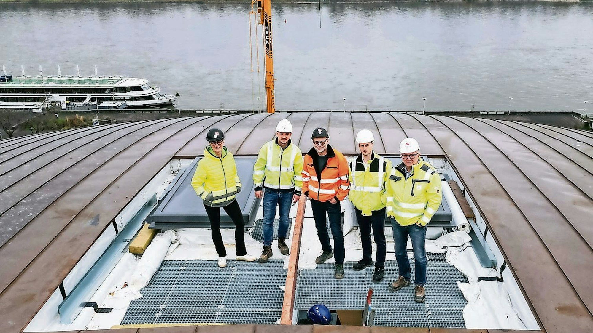 Projektleiter Steffen Göbel (Mitte) und Mitstreiter auf dem Kuppeldach der Halle: Sie stehen auf der Abdeckung des Fortlufthofs, über den im Brandfall die Entrauchung des Gebäudes erfolgt.