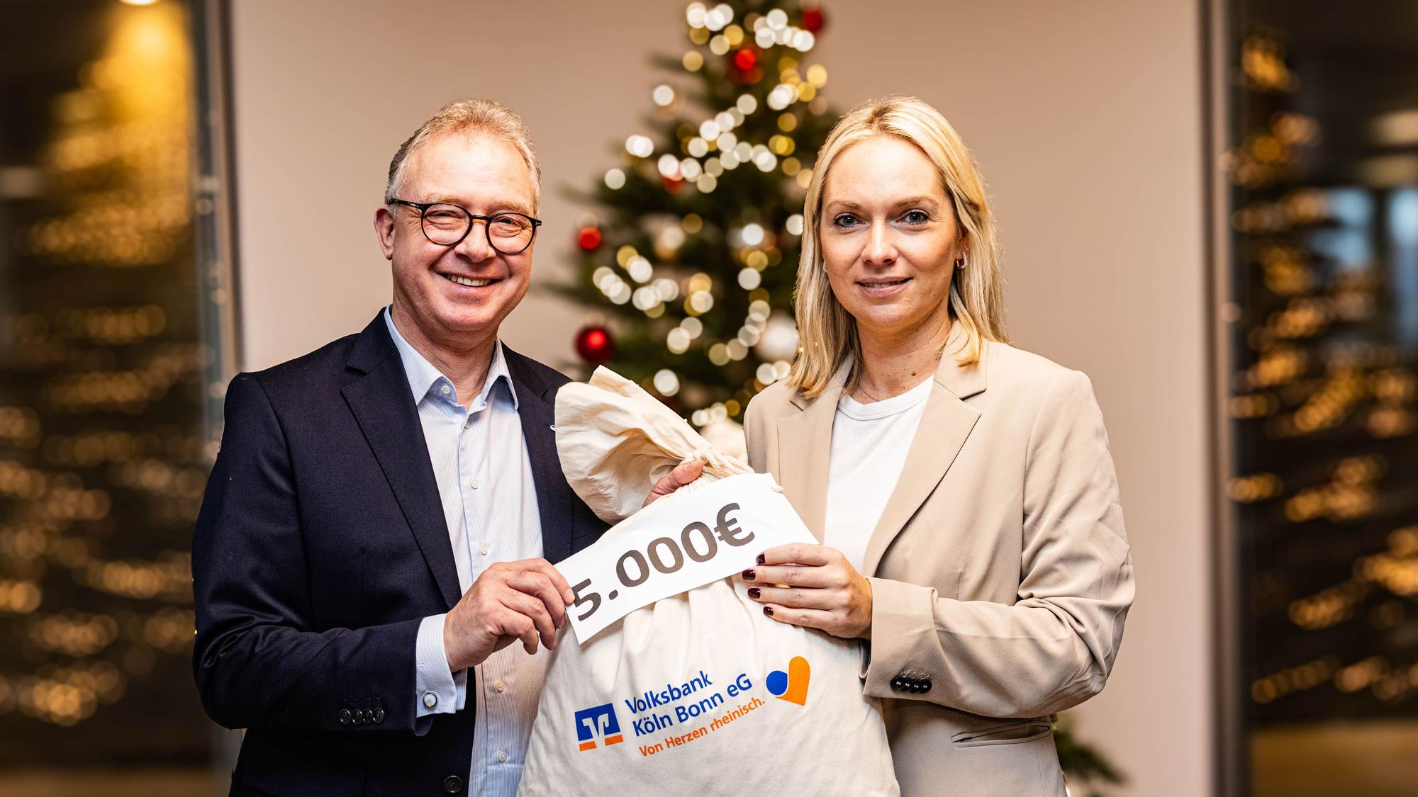 Ein Sack voll Geld für die Rundschau-Altenhilfe: Jürgen Pütz, Vorstandsvorsitzender der Volksbank Köln Bonn, überreicht Julia Heinen, Vorsitzende der Altenhilfe, symbolisch die Spende.