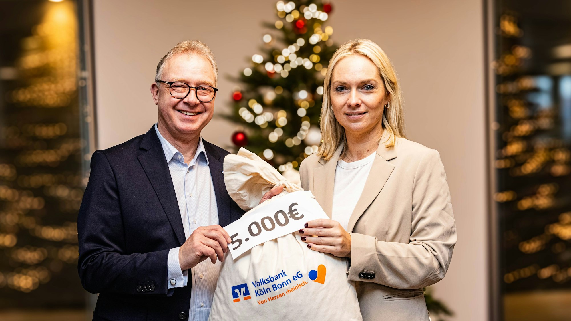 Ein Sack voll Geld für die Rundschau-Altenhilfe: Jürgen Pütz, Vorstandsvorsitzender der Volksbank Köln Bonn, überreicht Julia Heinen, Vorsitzende der Altenhilfe, symbolisch die Spende.