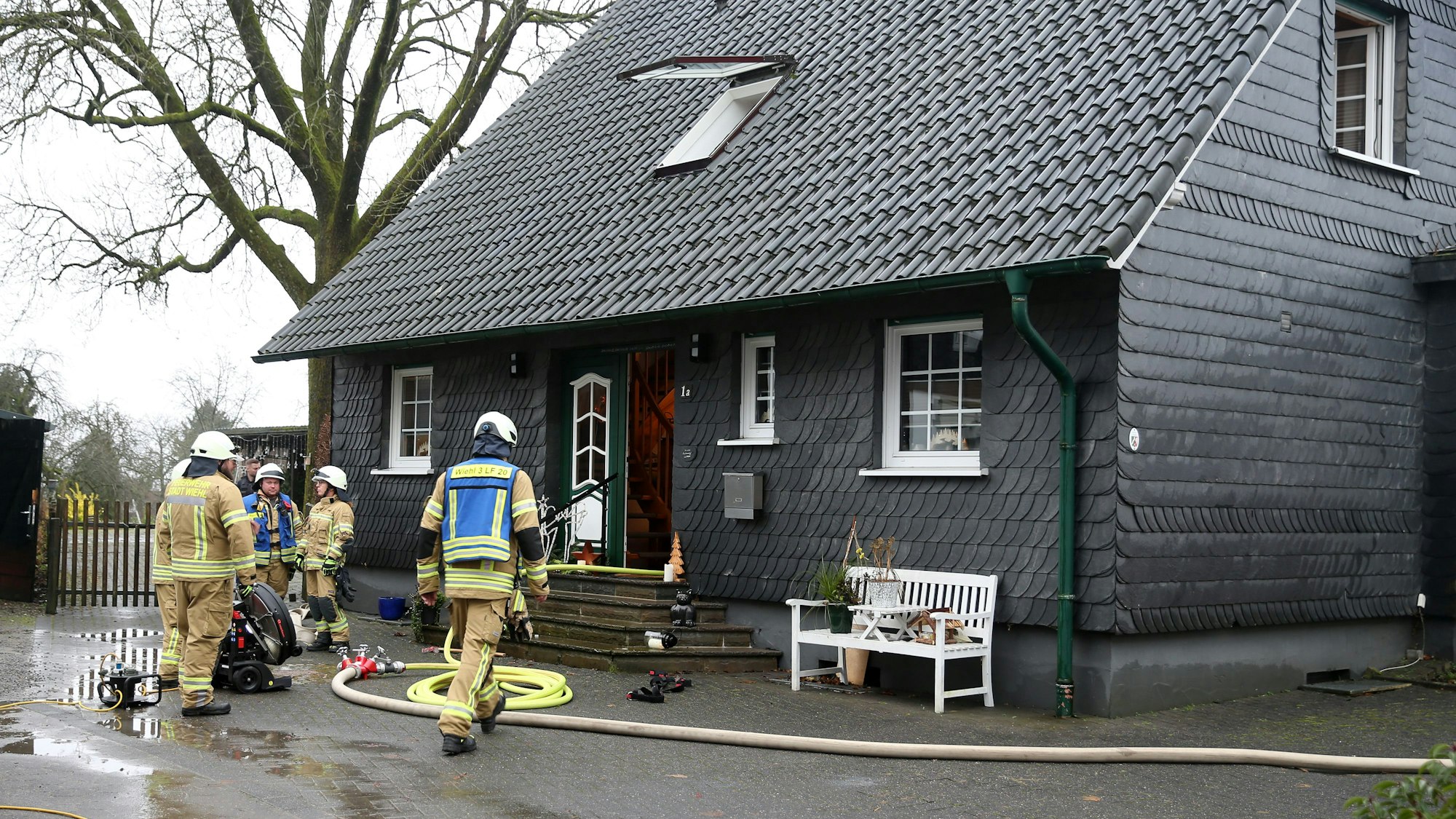 Feuerwehrleute stehen bei einem Einsatz vor einem Haus.