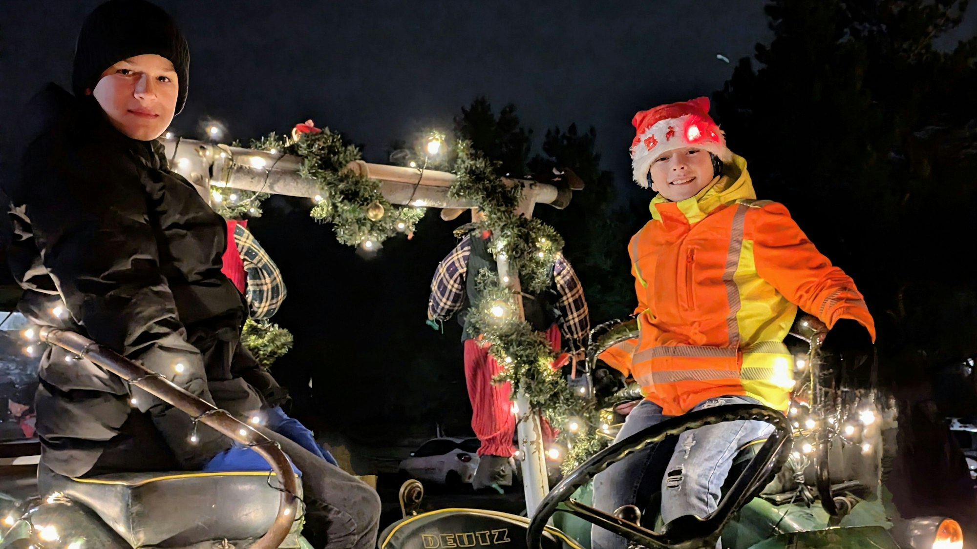 Jan (links) und sein Freund Tiago sitzen auf einem beleuchteten Traktor.