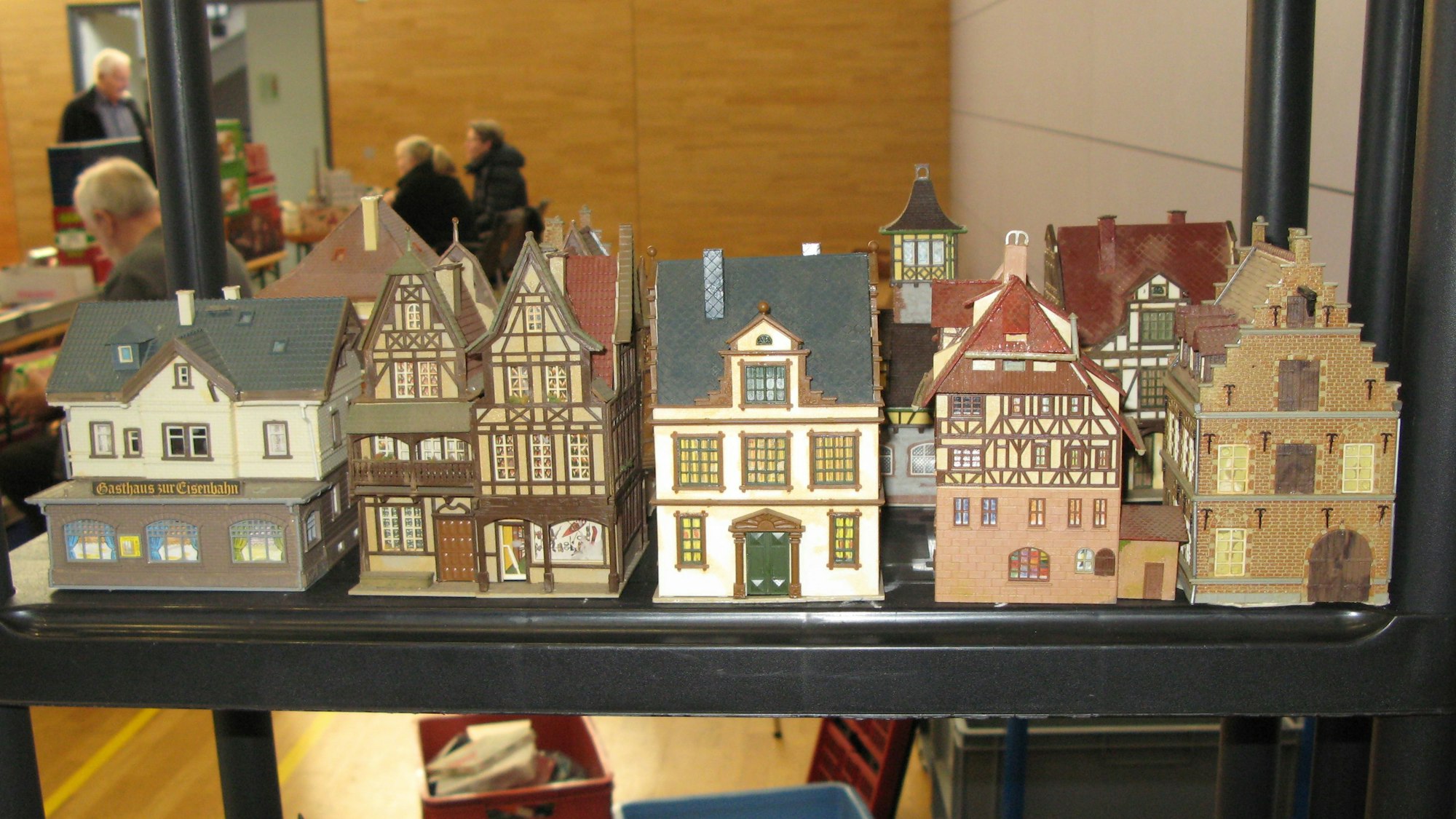 Fünf Miniaturhäuser stehen nebeneinander in einem Regal.