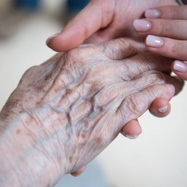 Eine jung Frau hält die Hand einer alten Frau.
