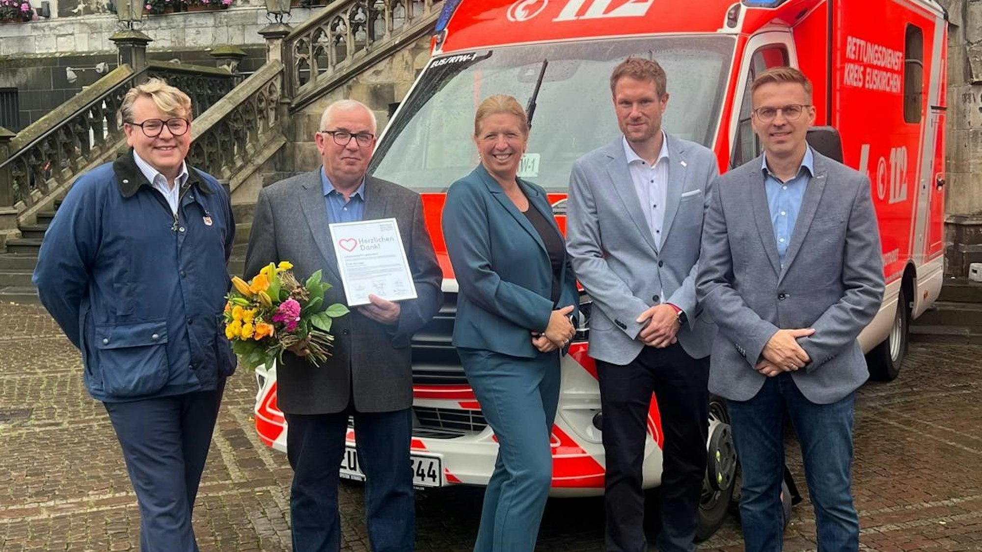 Das Bild zeigt die Delegation von der Euskirchener Kreisverwaltung und den Corhelper vor einem Rettungswagen.