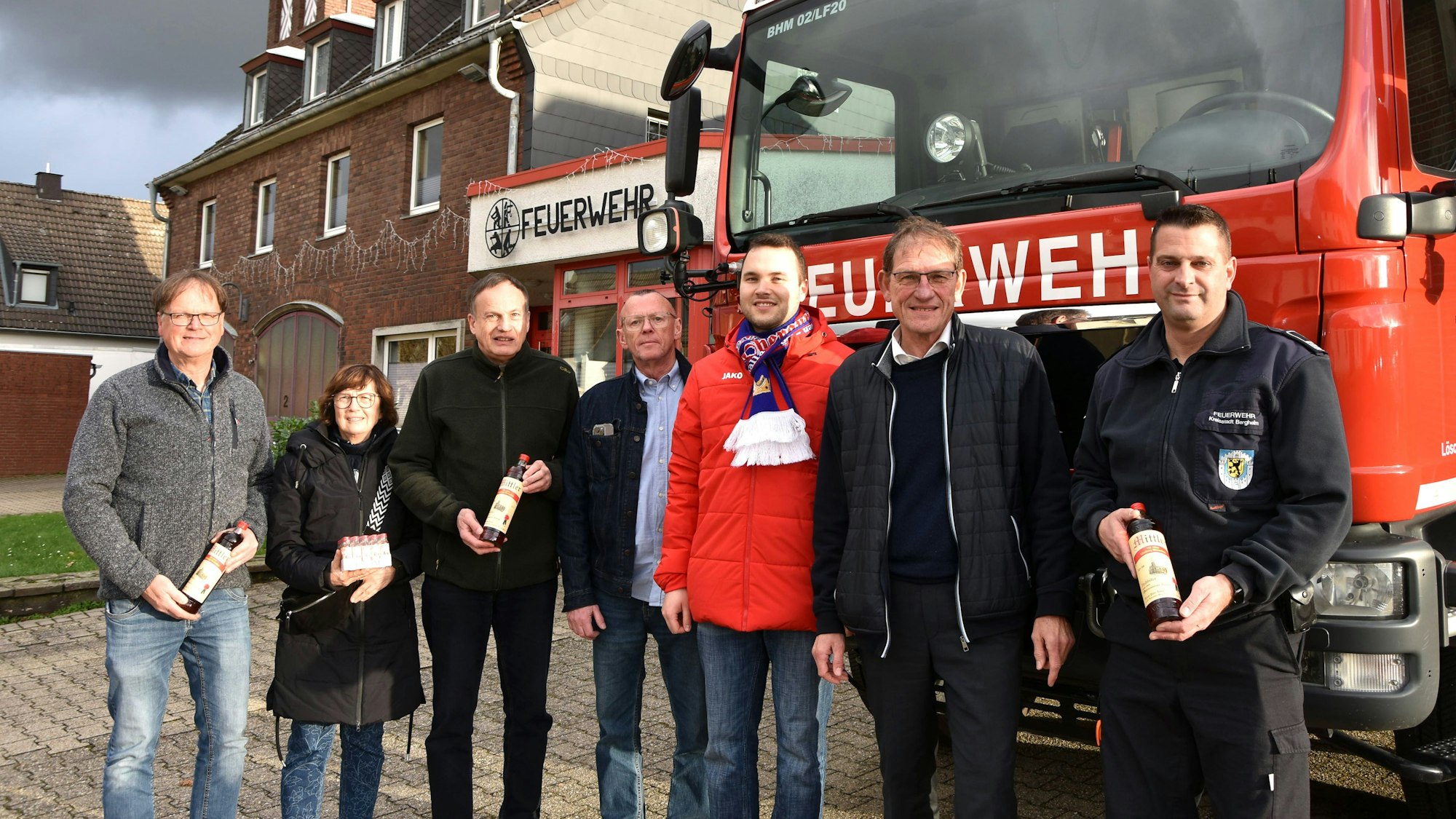 Das Foto zeigt mehrere Menschen vor einem Feuerwehrfahrzeug.