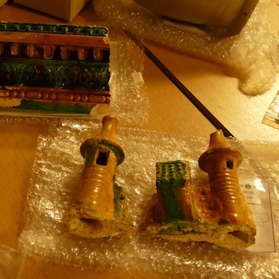 Auf einem Tisch liegen turmförmige und bunt bemalte Keramikbruchstücke.