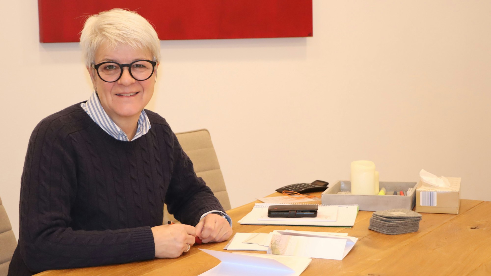 Auf dem Bild ist die Bestatterin zu sehen, die an einem großen Tisch sitzt.