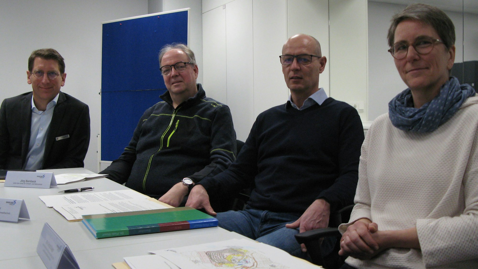 Drei Männer und eine Frau von der Kreisverwaltung an einem Tisch, auf dem schriftliche Unterlagen liegen.