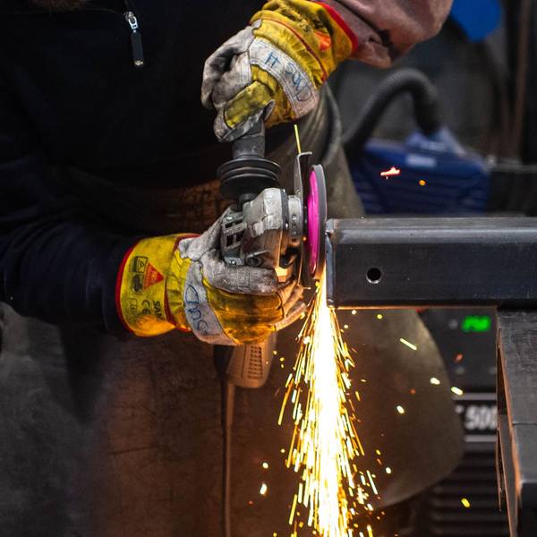 Das Bild zeigt einen Metallbauer, der eine Metallkonstruktion abschleift.